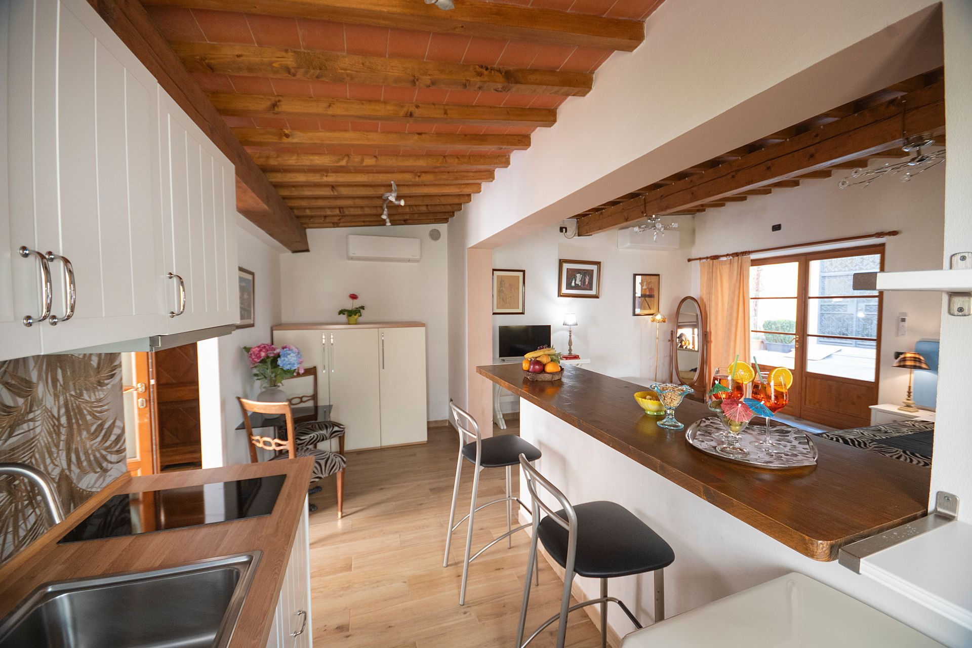 Modern kitchen with white cabinets, wooden ceiling beams, and a breakfast bar with stools