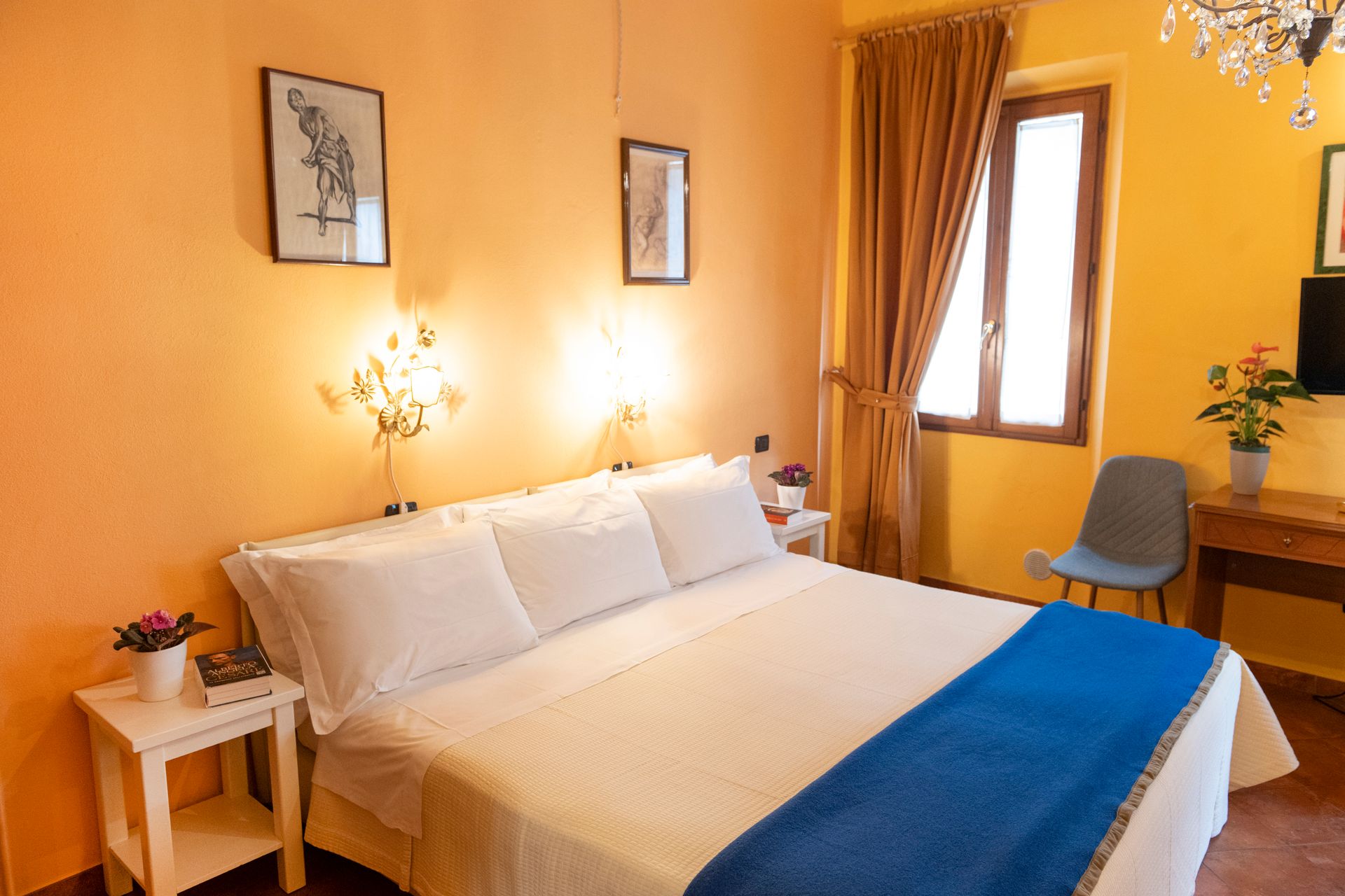 Cozy bedroom with white bed, blue throw, warm yellow walls, and a window with curtains