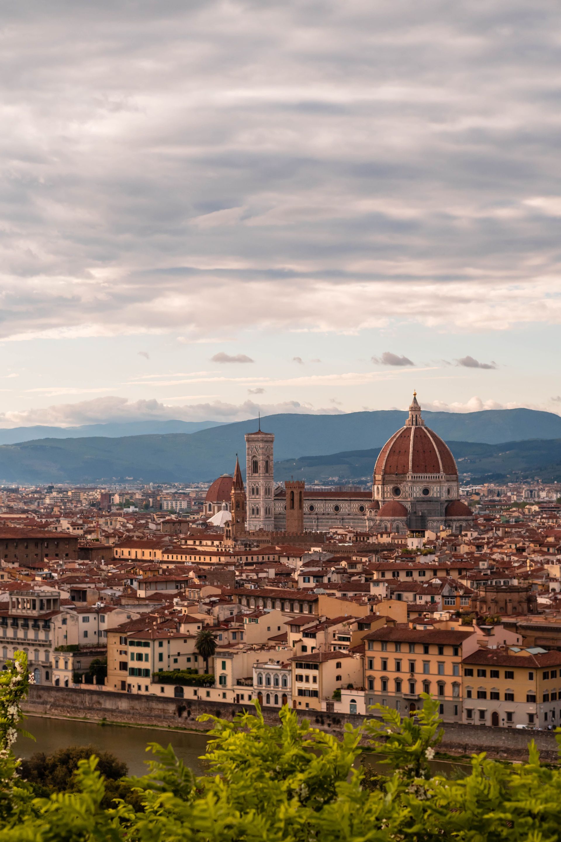 Florence skyline with the Duomo and bell tower under a cloudy sky, viewed from above