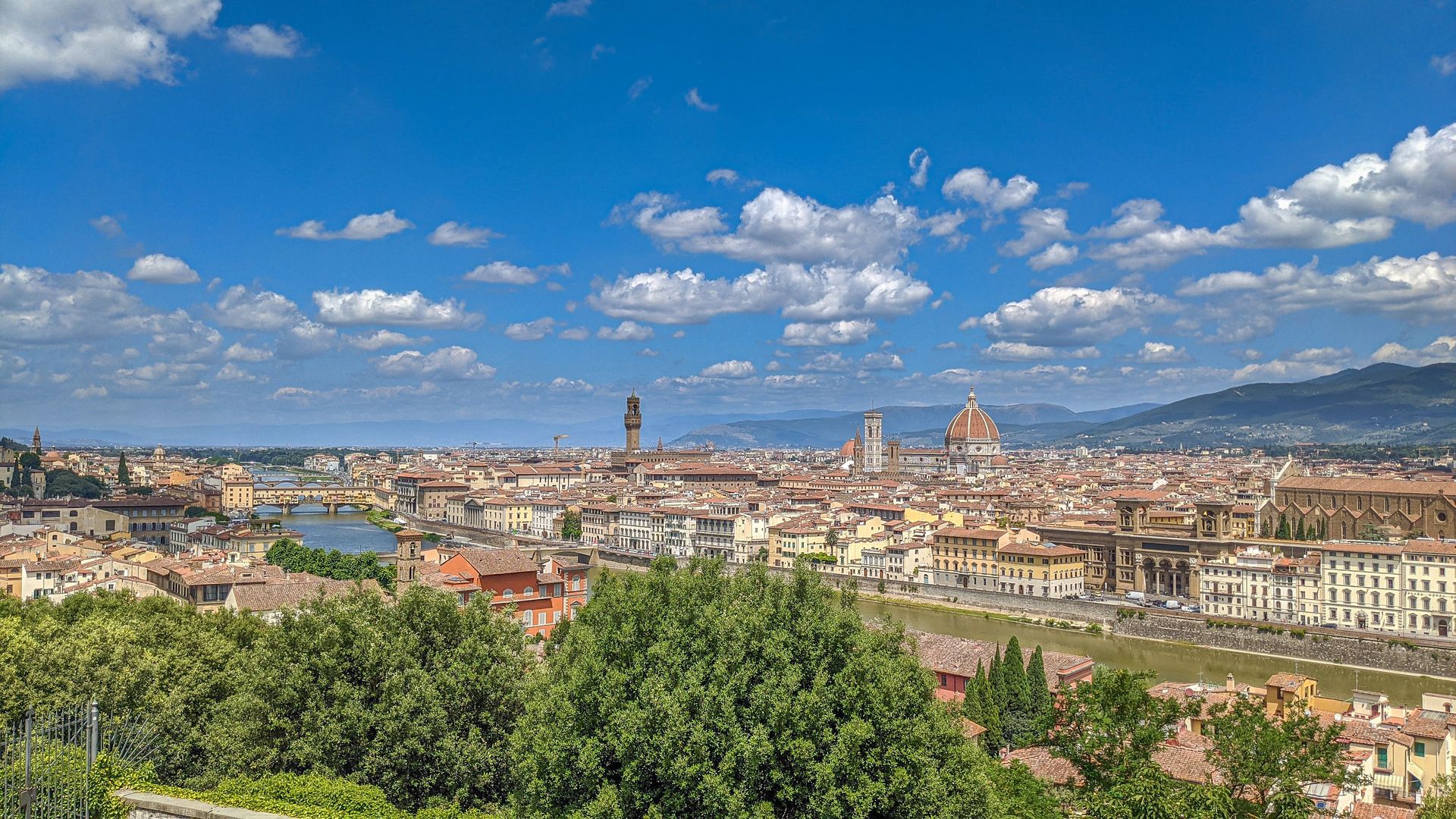 Panoramic cityscape of Florence with the Duomo and rooftops under a blue sky with clouds