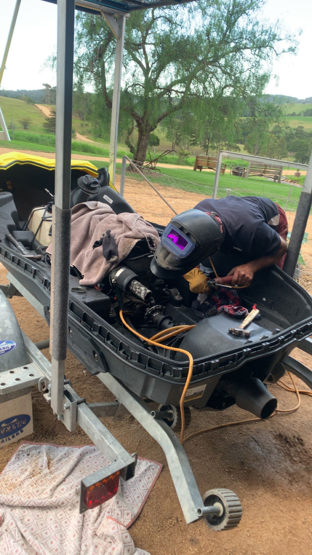 Person Welding Inside a Black Vehicle Chassis on a Trailer, Wearing a Welding Helmet — Bodes All Mechanical In Candelo, NSW