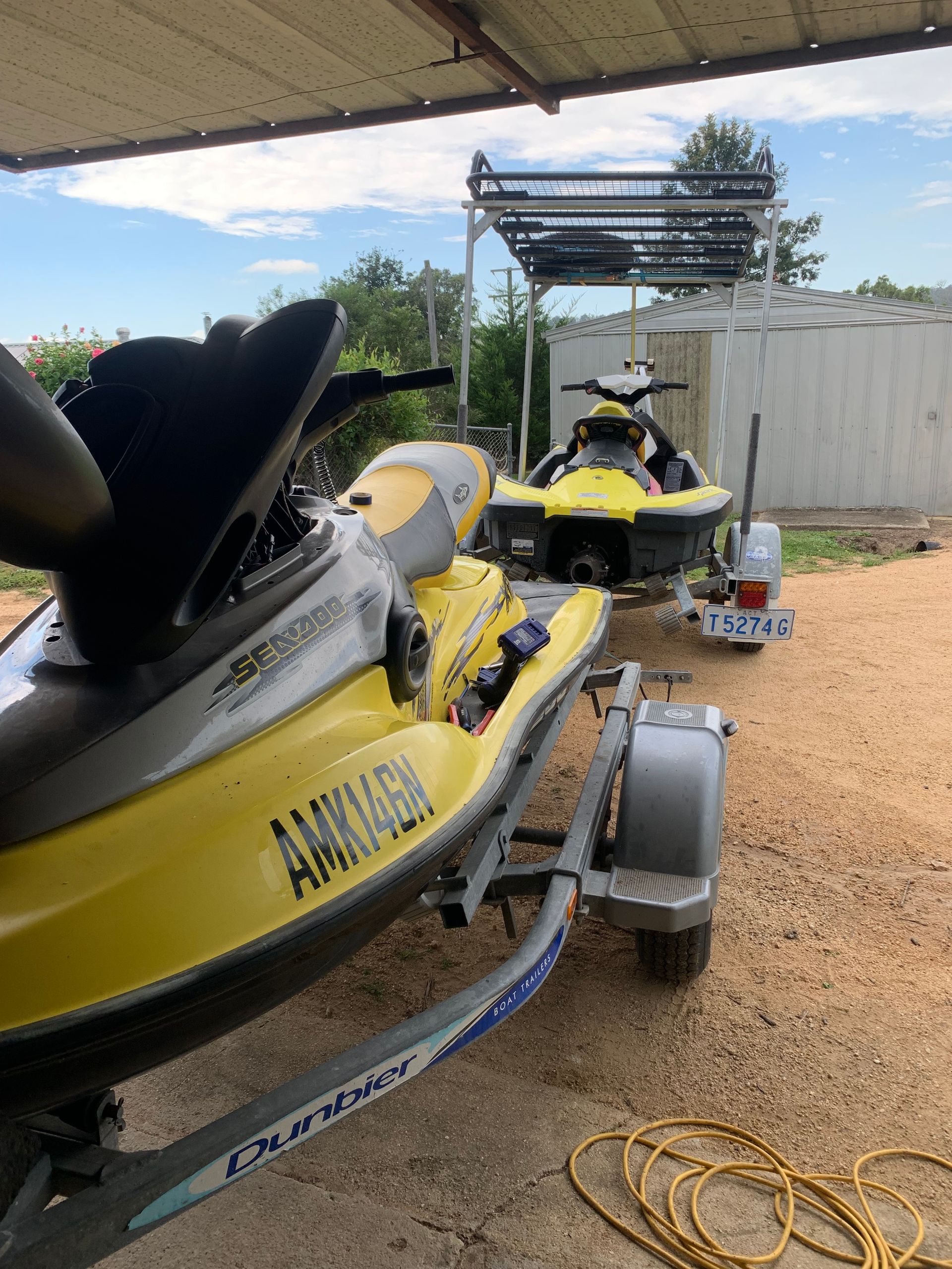 Two Yellow and Gray Jet Skis on Trailers Under a Metal Canopy — Bodes All Mechanical In Bermagui, NSW