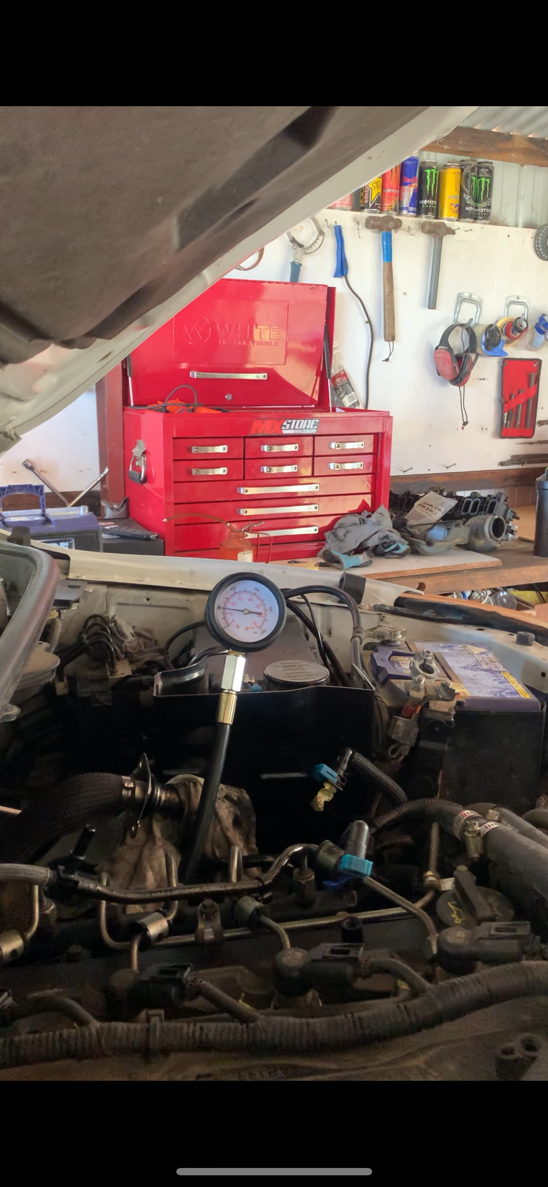 Engine in a garage with a pressure gauge connected. A red toolbox and tools are in the background. — Bodes All Mechanical In Bega, NSW