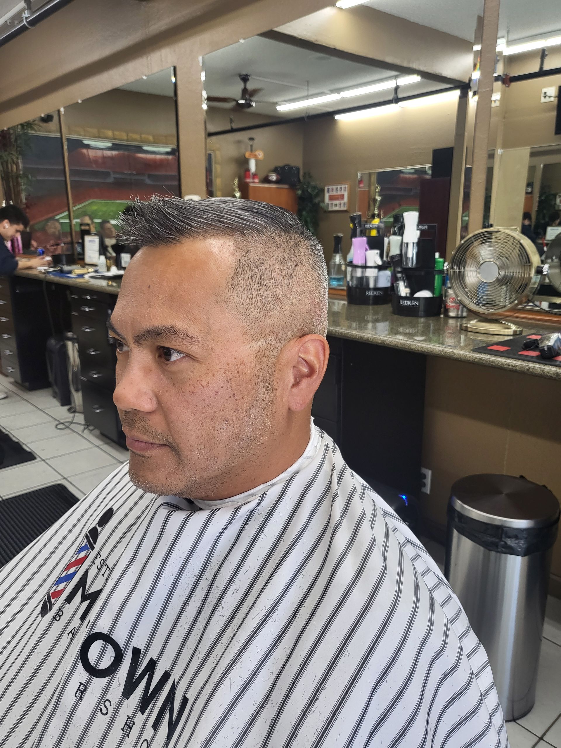 A man is getting his hair cut at a barber shop.