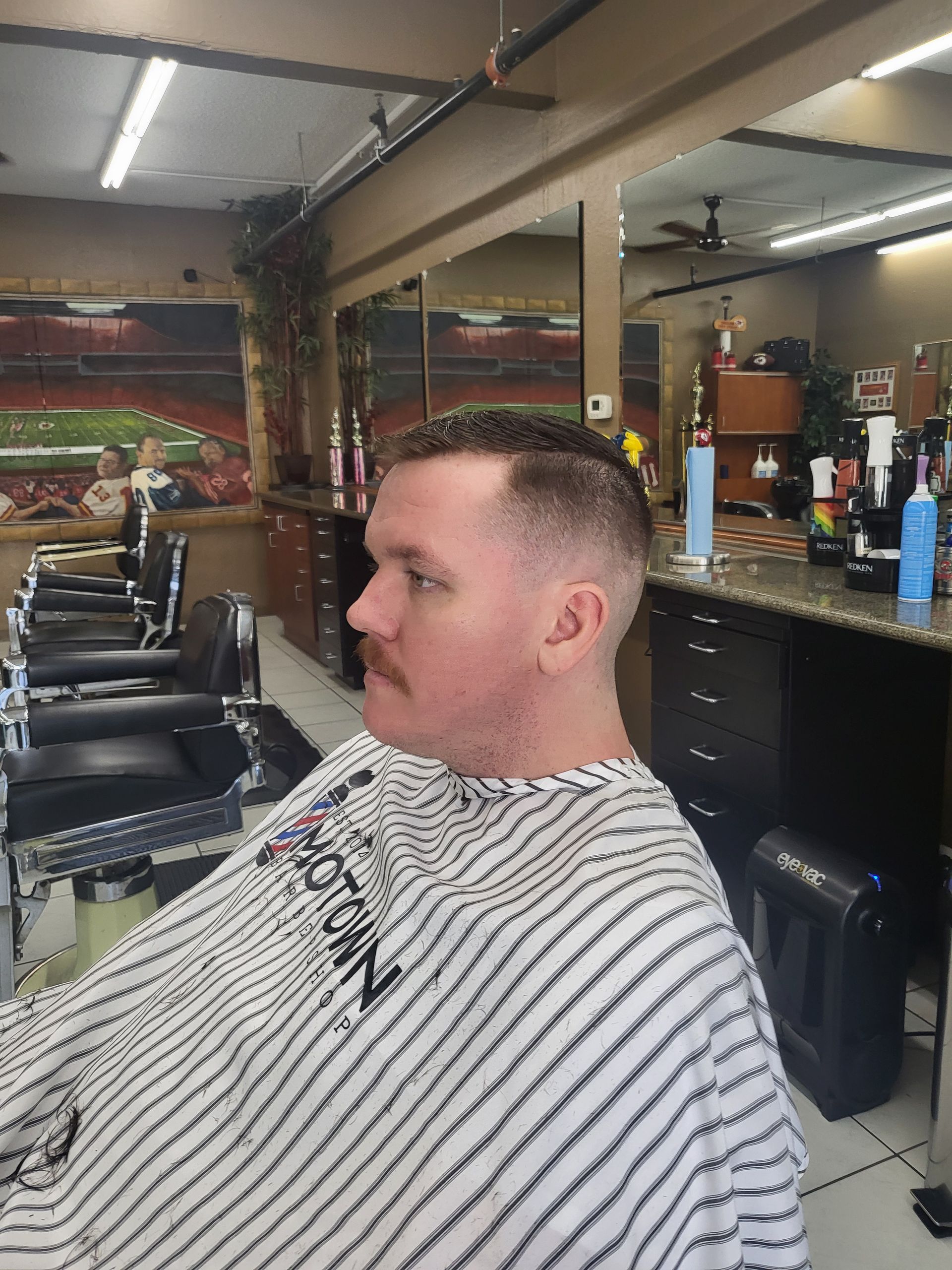 A man is getting his hair cut at a barber shop.