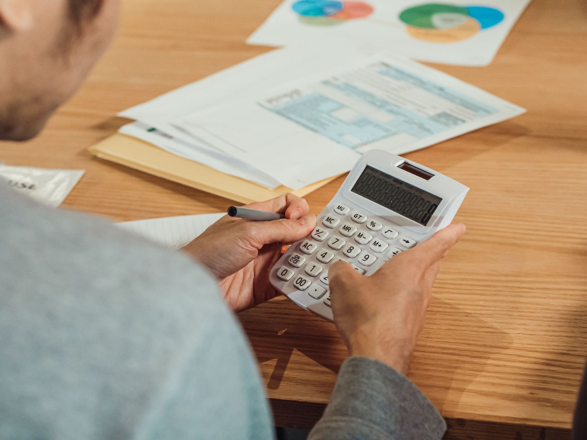 Hands using a calculator beside financial paperwork