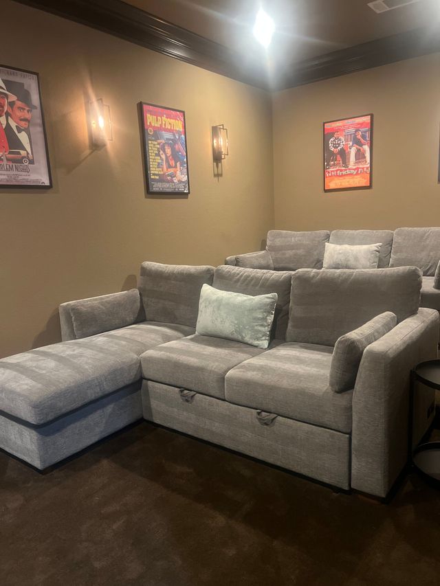 Cozy living room with a gray sectional sofa, dark wood floors, and framed wall art.