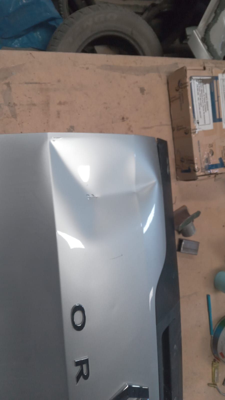 Baúl de auto color plata con una abolladura y la palabra
