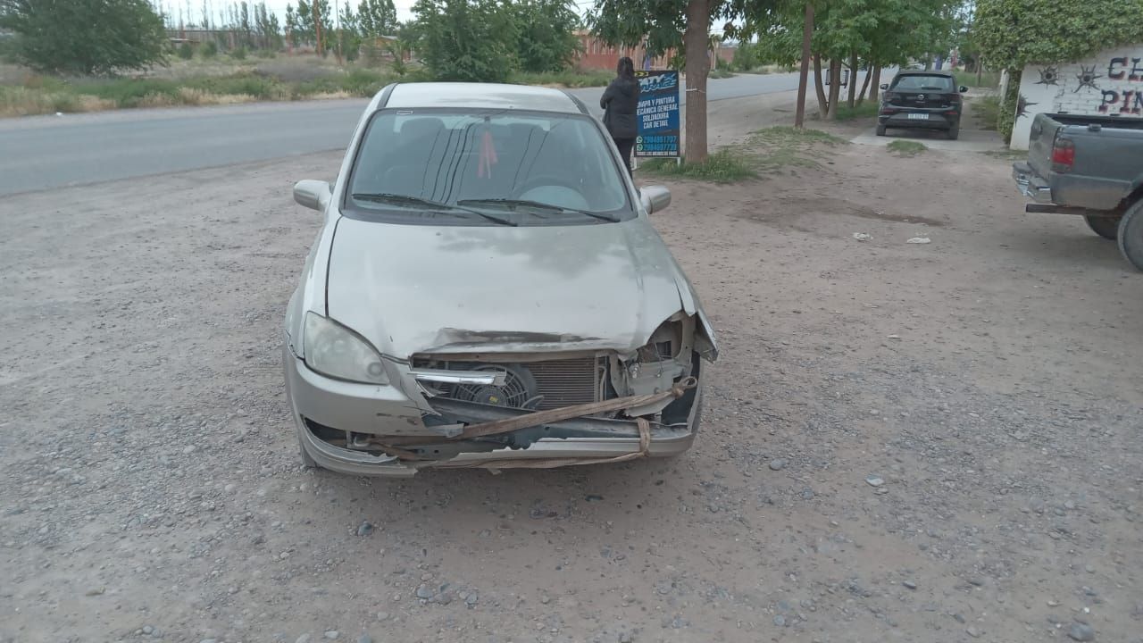 Un coche plateado dañado estaba estacionado en un camino de tierra, con la parte delantera muy dañada.