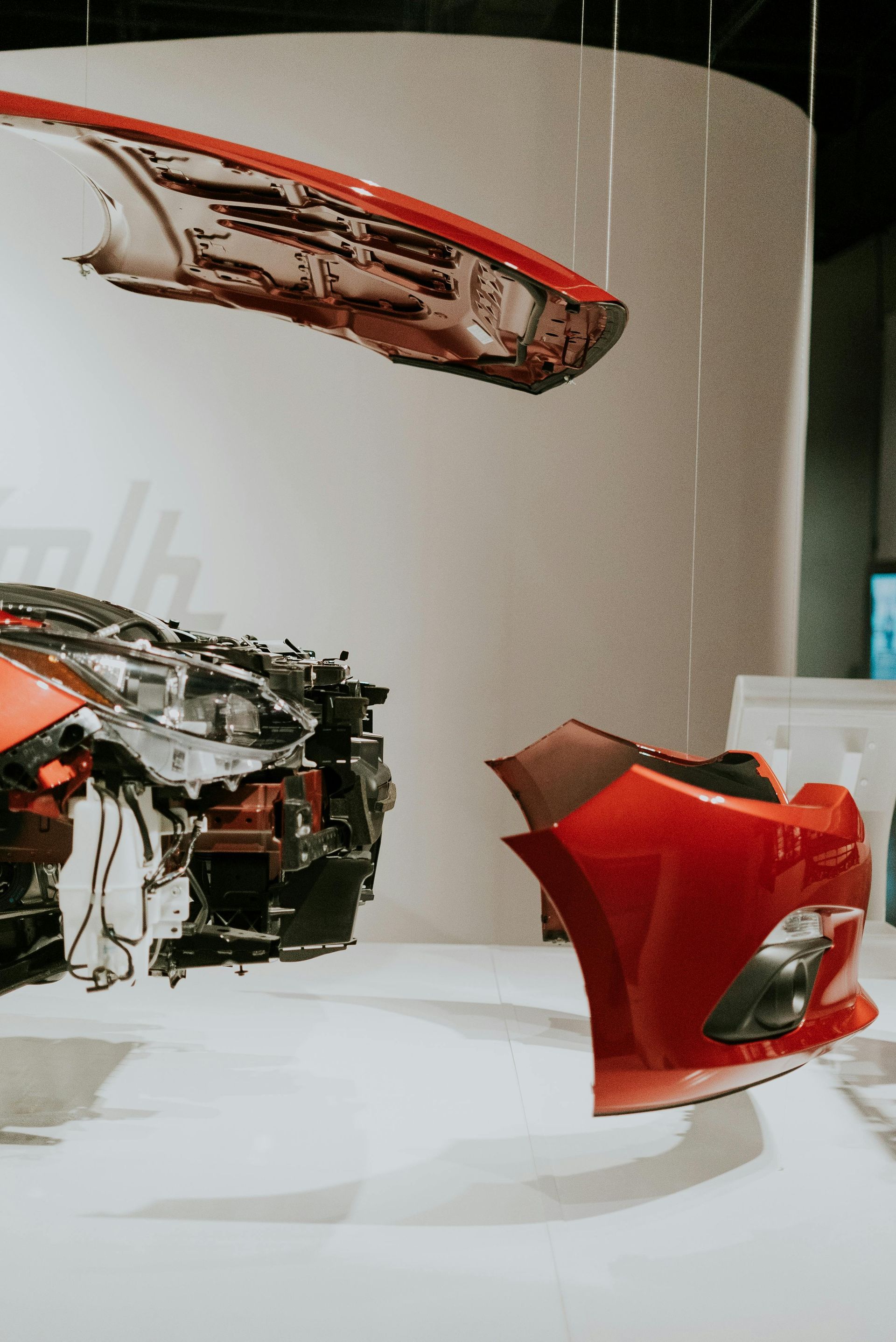 Partes de un automóvil rojo suspendidas en un museo, mostrando su construcción.