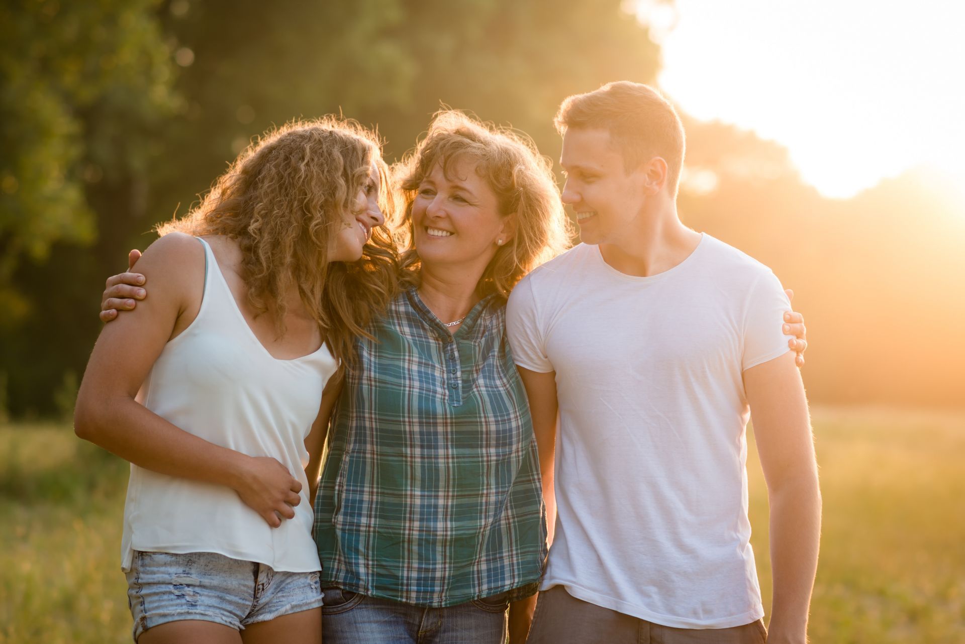A man and two women are standing next to each other in a field.