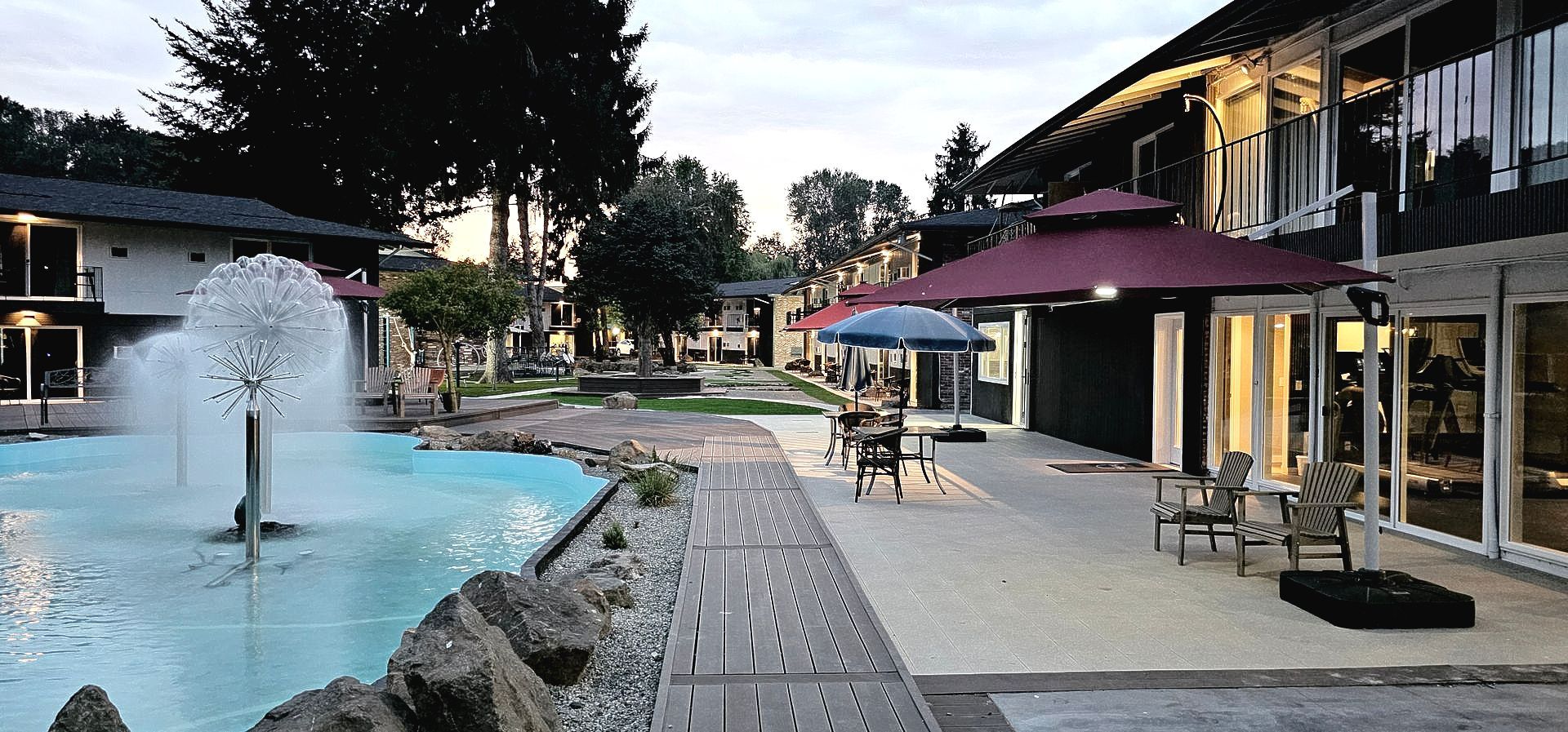 A hotel with a fountain and umbrellas in front of it