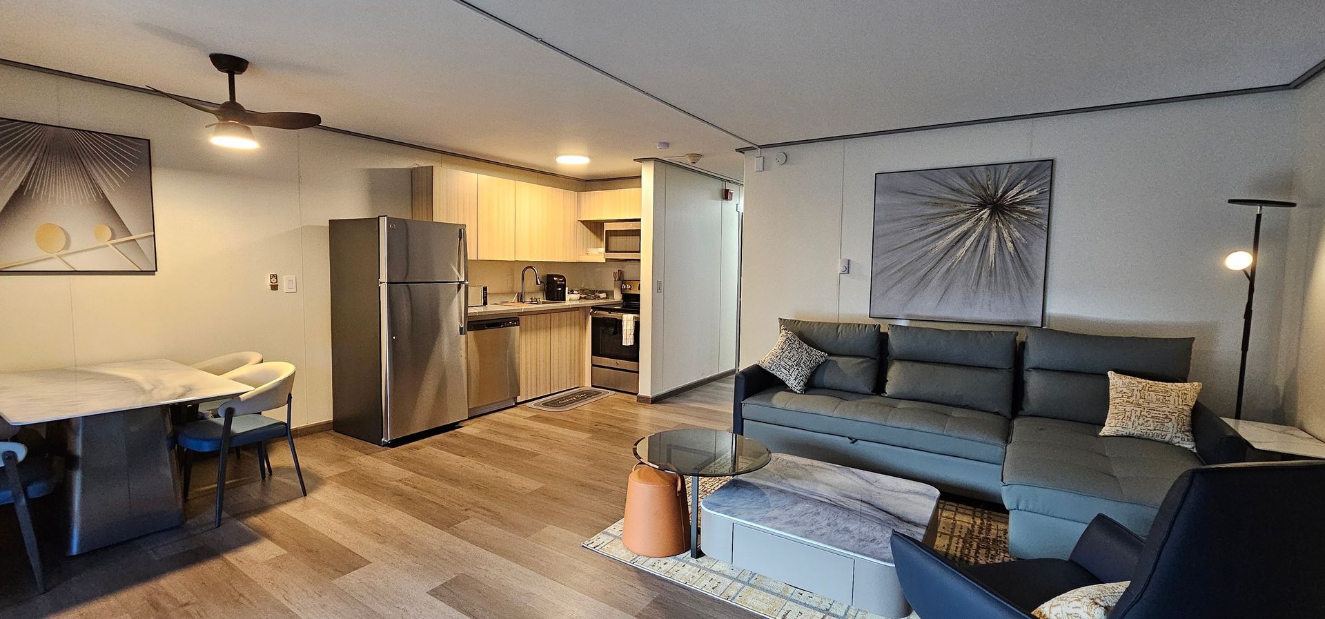 A living room with a couch , chairs , a table and a refrigerator.