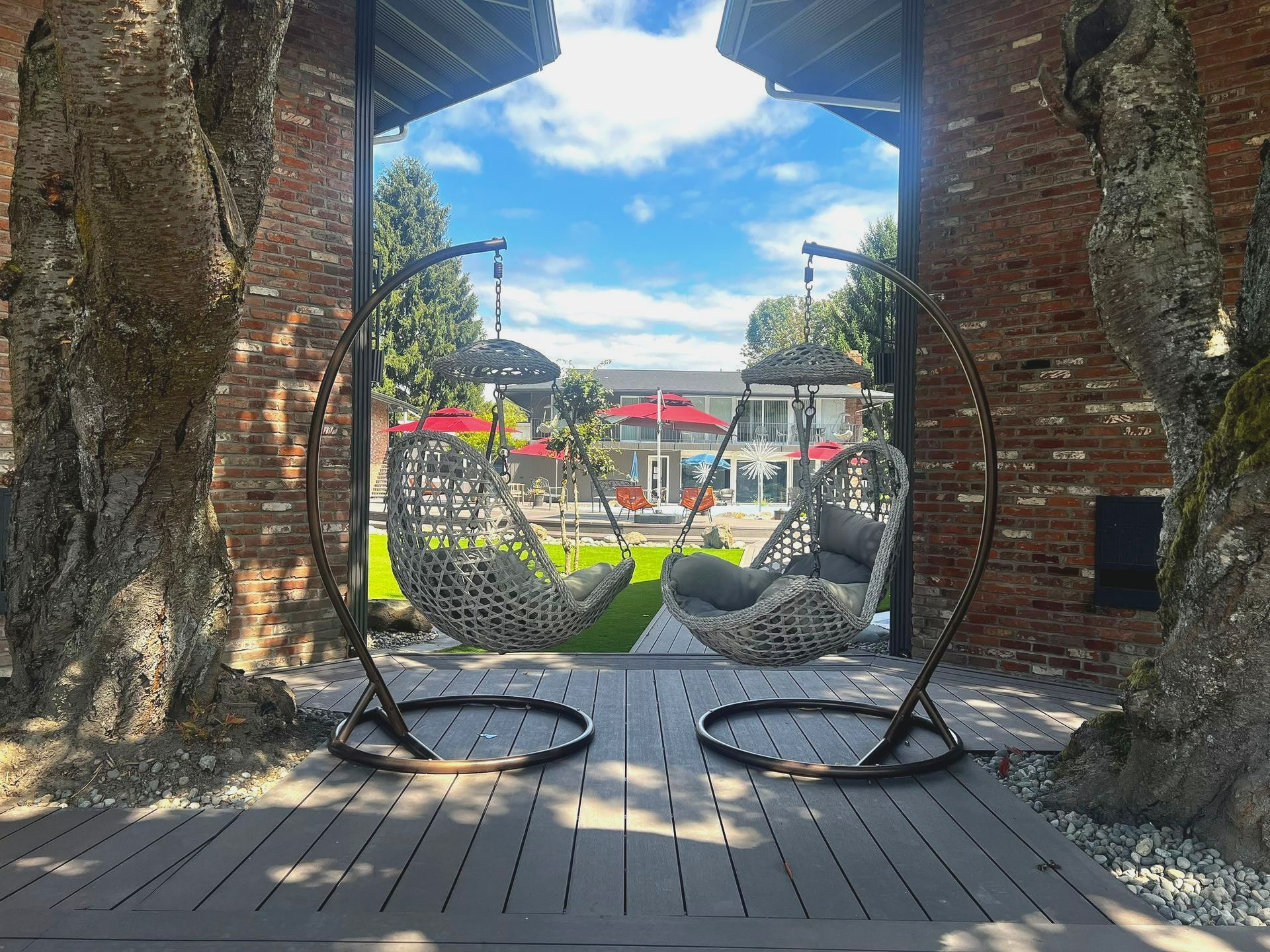Two hanging chairs are sitting on a wooden deck in front of a brick building.