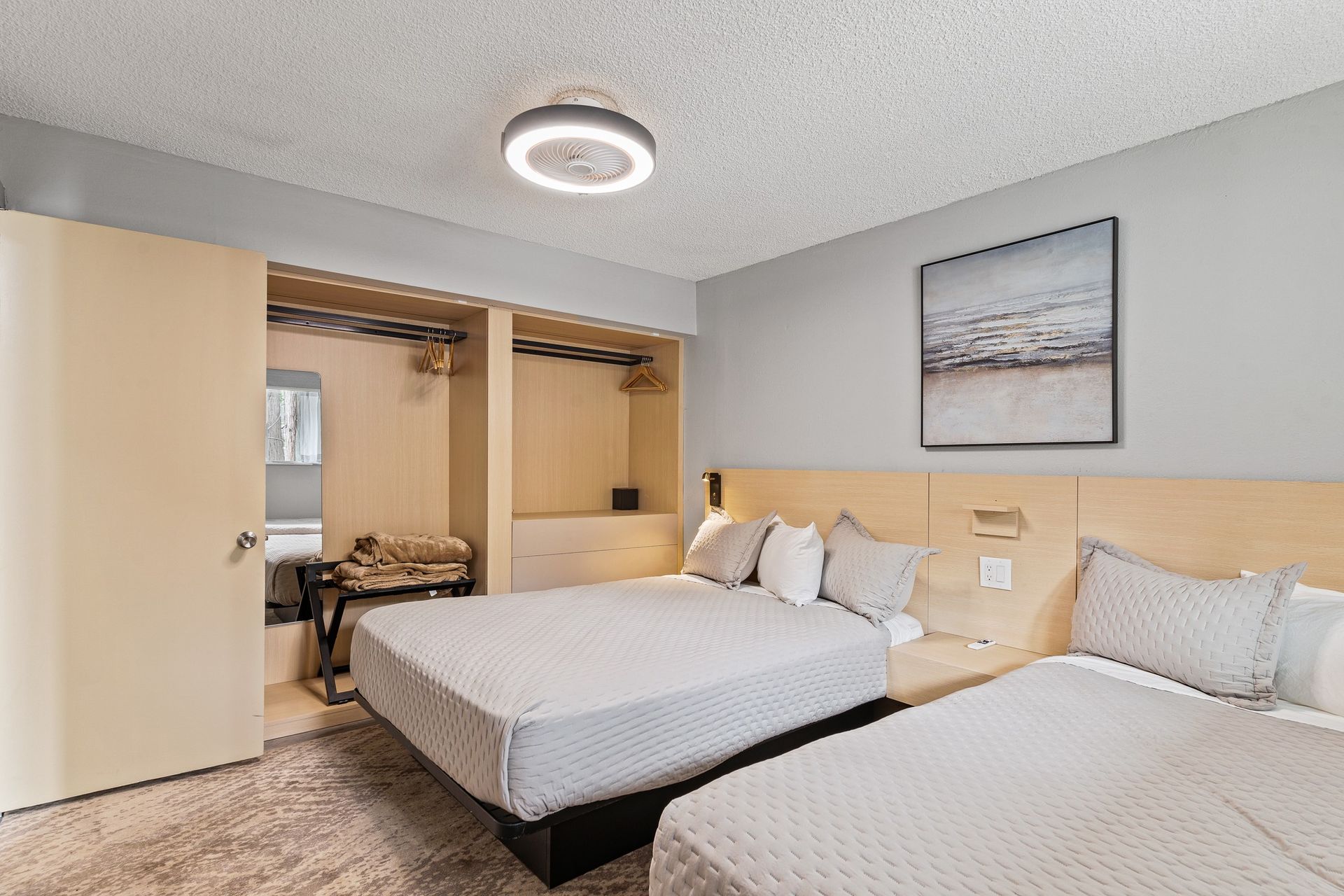 A hotel room with two beds and a painting on the wall.