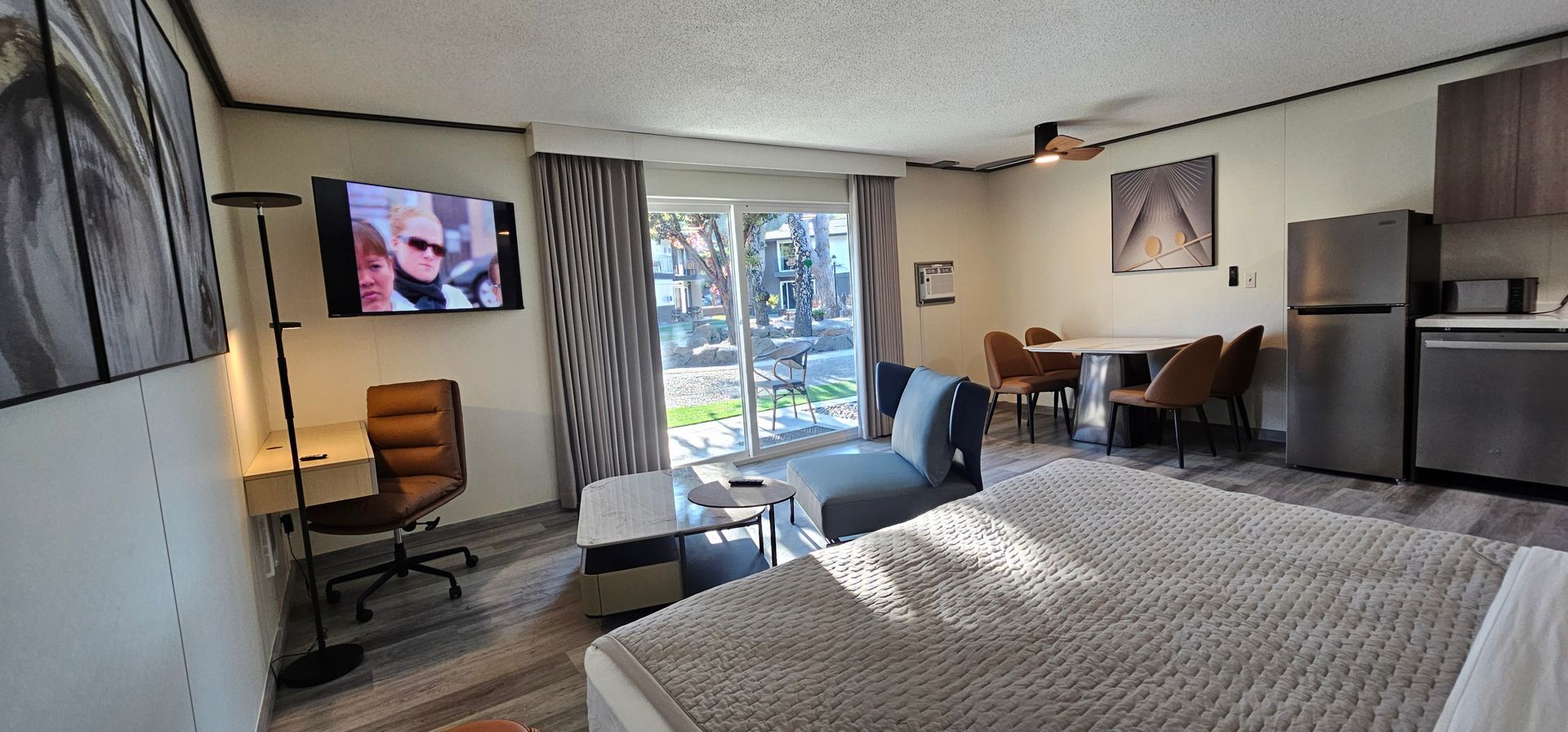 A hotel room with a king size bed , a flat screen tv , a table and chairs.