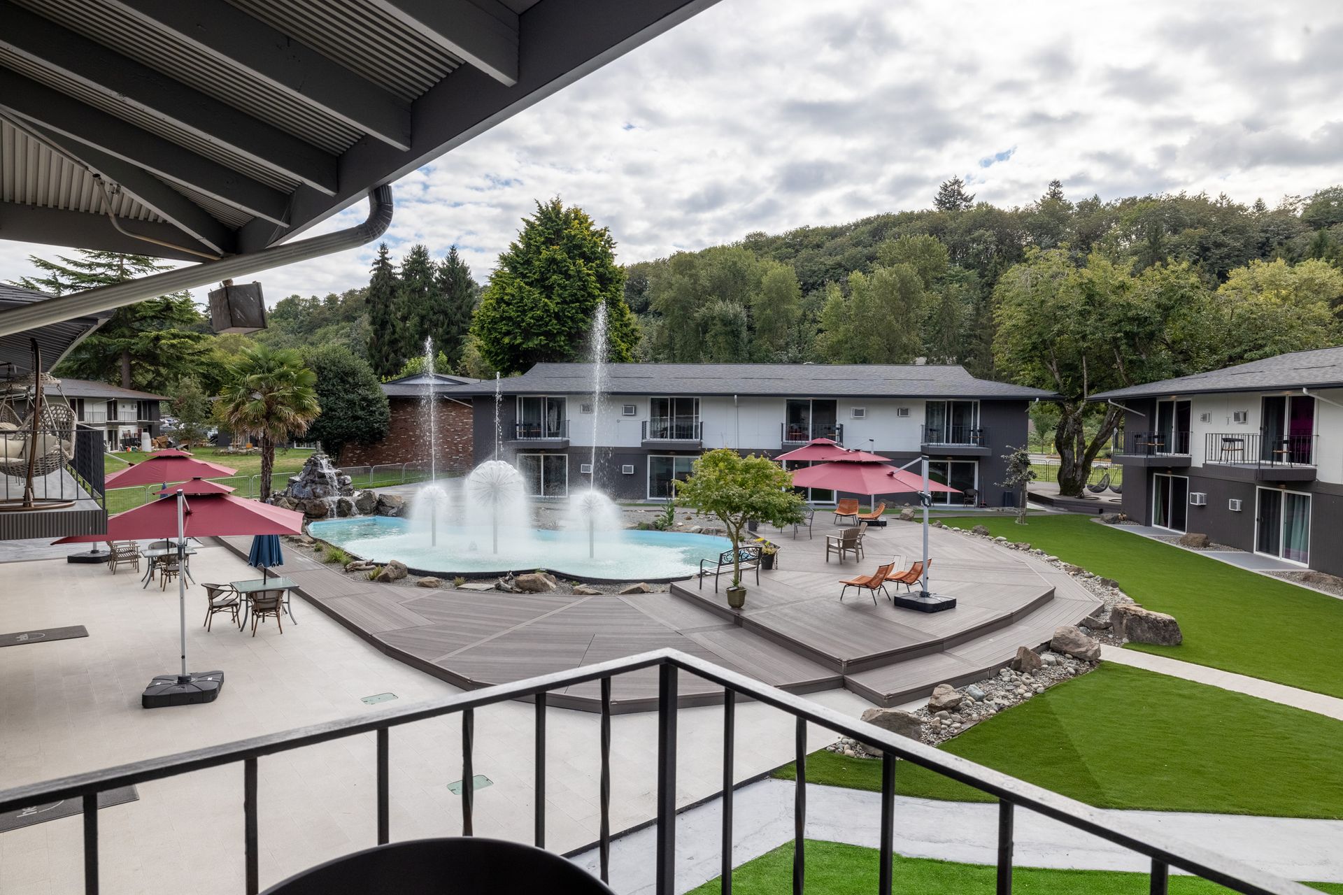 A balcony overlooking a hotel with a fountain and a pool.