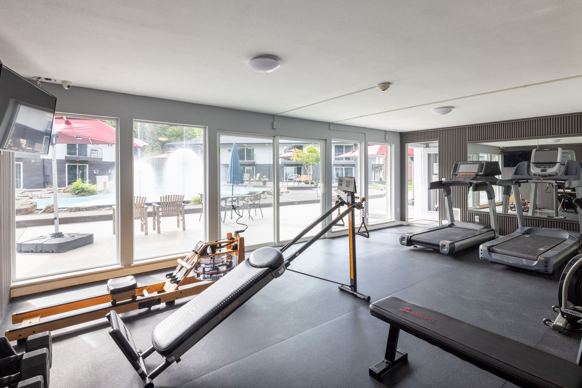 A gym with treadmills , a bench , and a rowing machine.