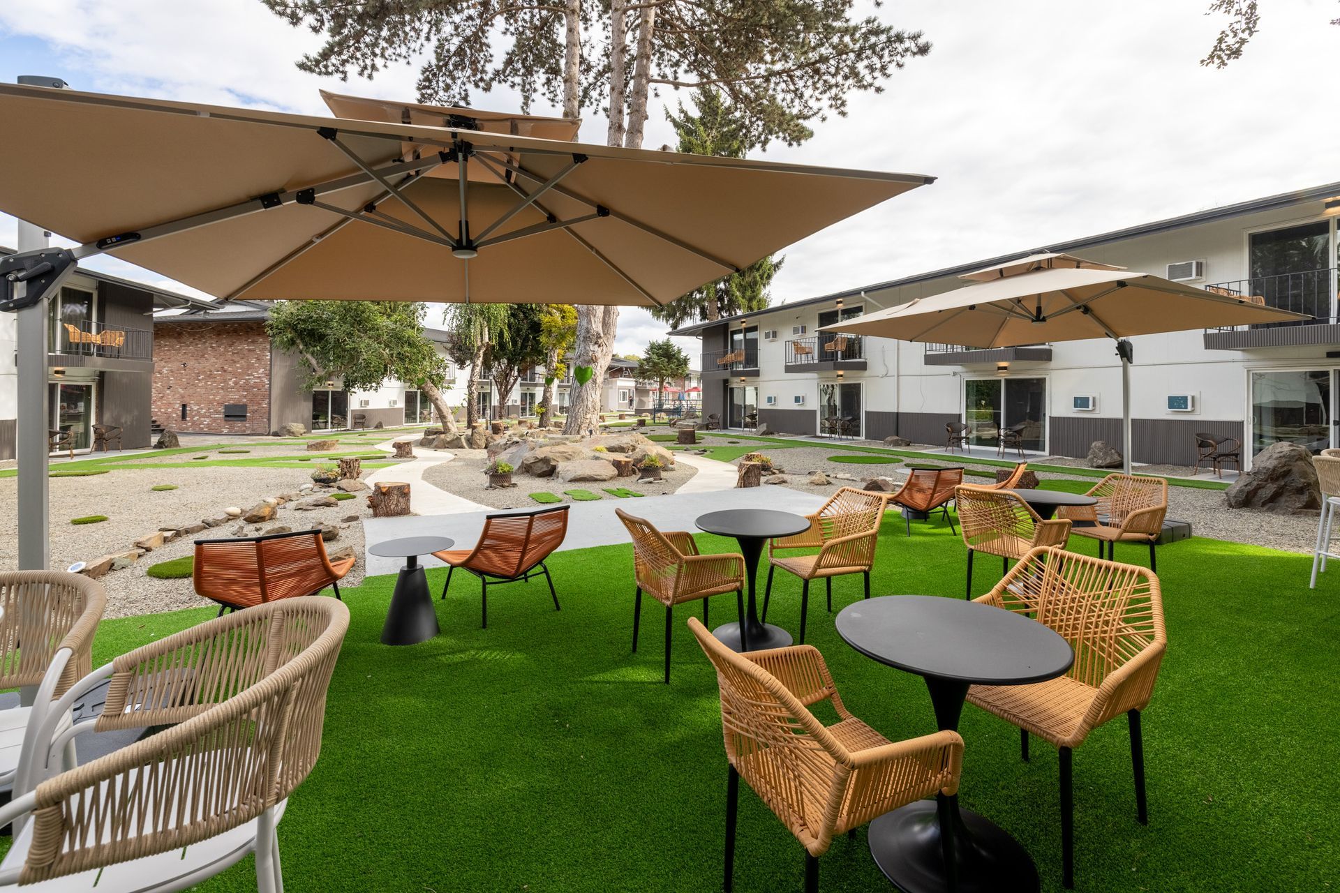 A patio area with tables and chairs under umbrellas in front of a building.