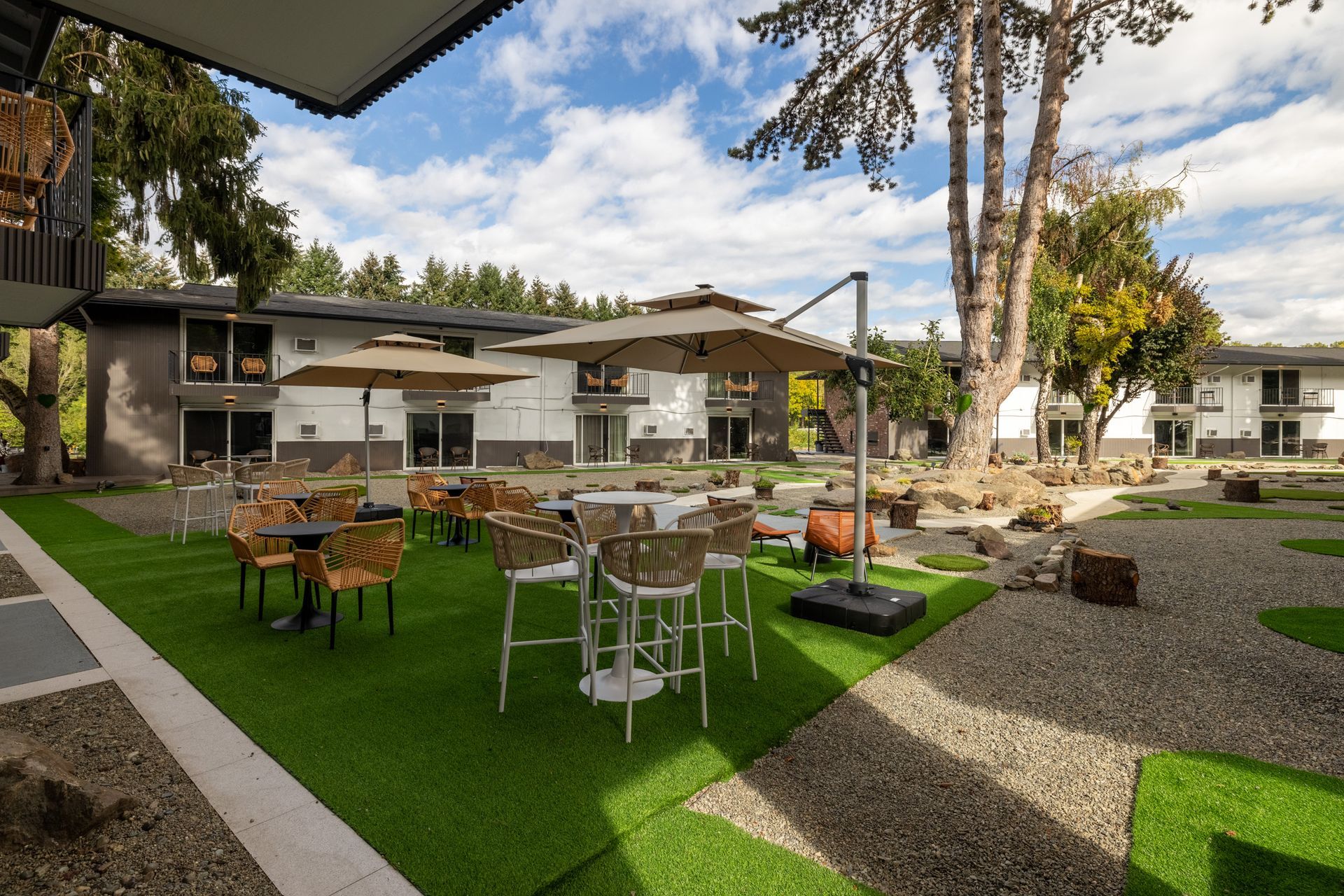 A patio area with tables and chairs and umbrellas in front of a building.