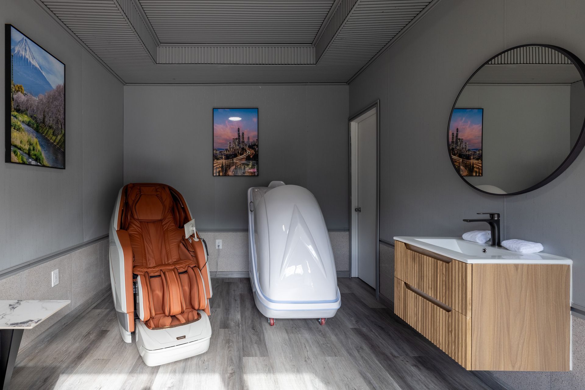 A bathroom with a massage chair , sink and mirror.