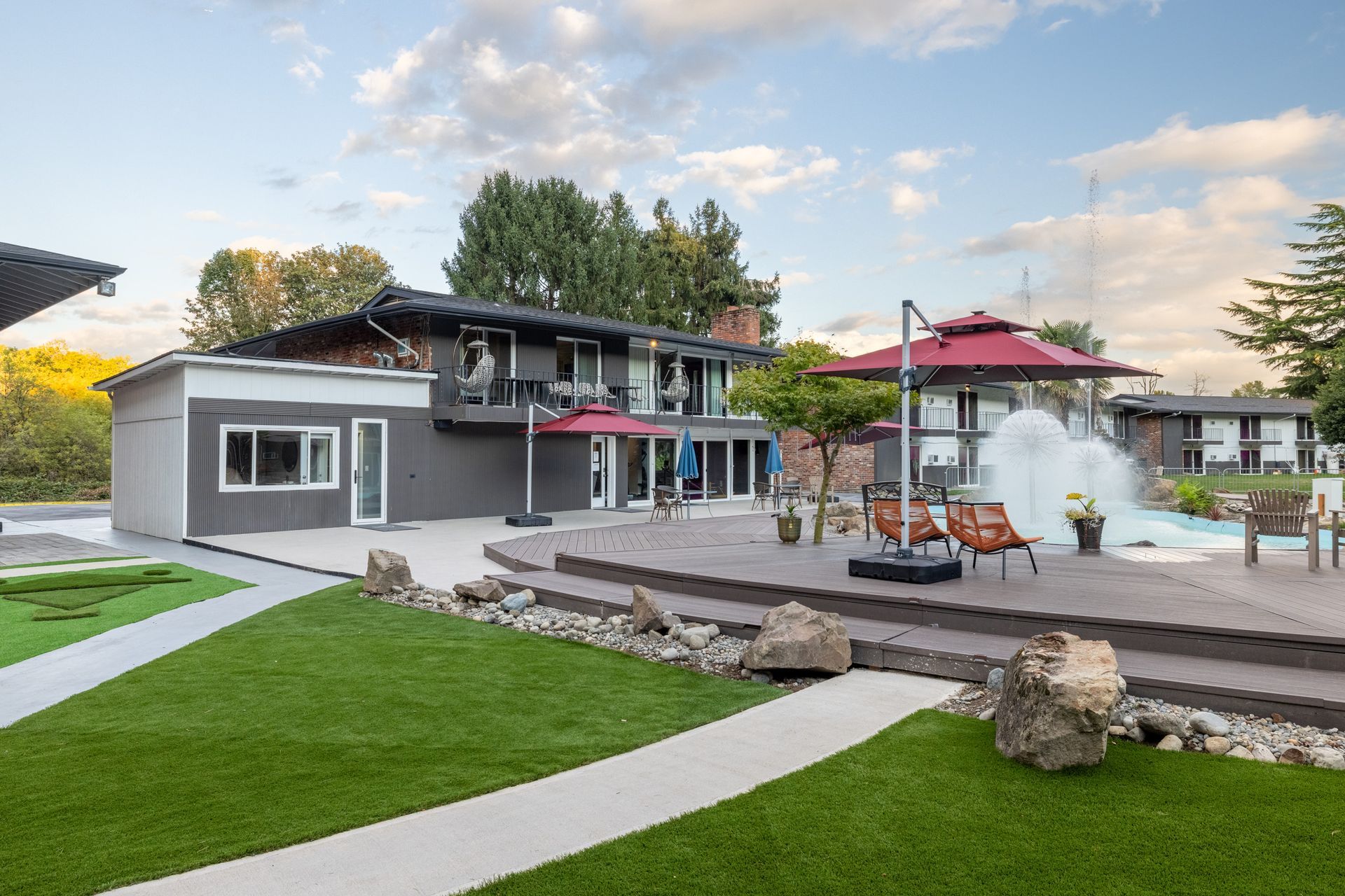 A large house with a swimming pool and umbrellas in front of it.