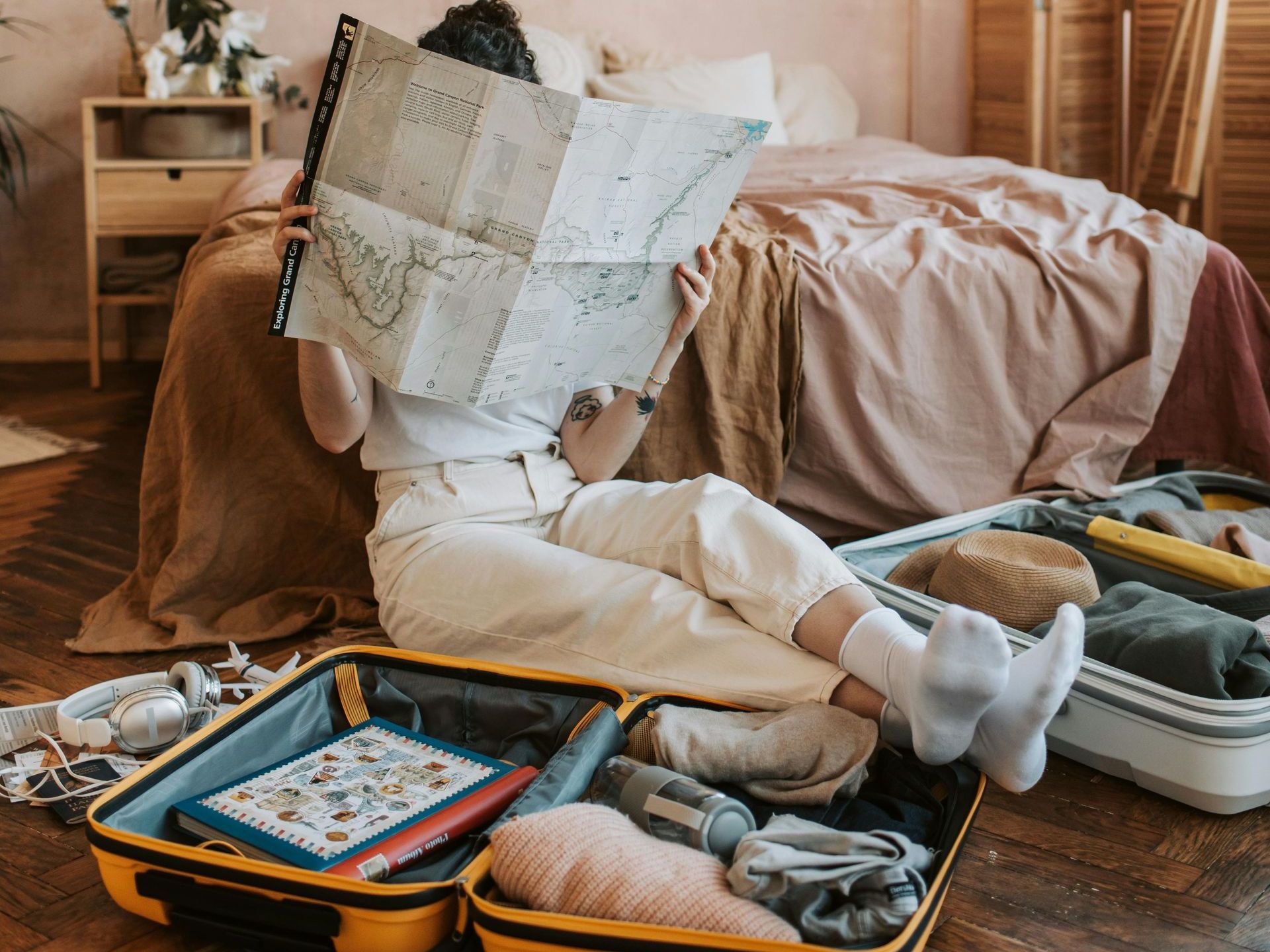 Tourist packing her suitcase carefully while reading a map, ready for a new adventure.