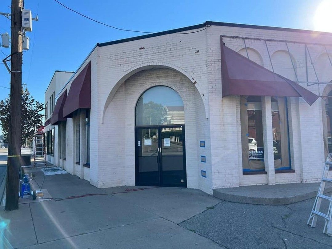 A white brick building with a red awning on the side of it.