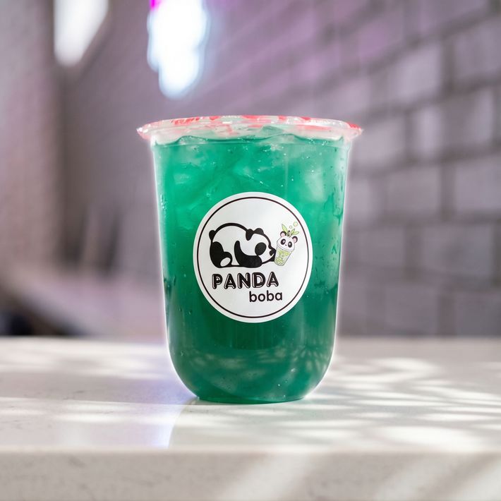 Green iced boba drink in a clear cup with a Panda Boba logo on a white table