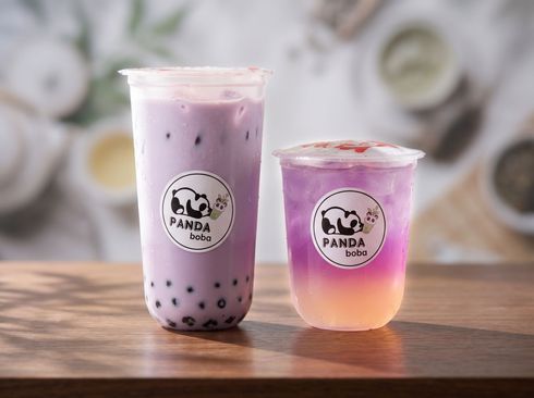 Two bubble tea drinks on a wooden table, one purple and one pink-yellow gradient, with panda logos