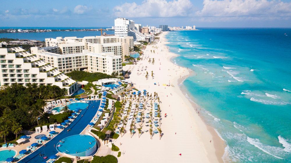 Aerial view of Cancún beach with turquoise water, white sand, and hotels.