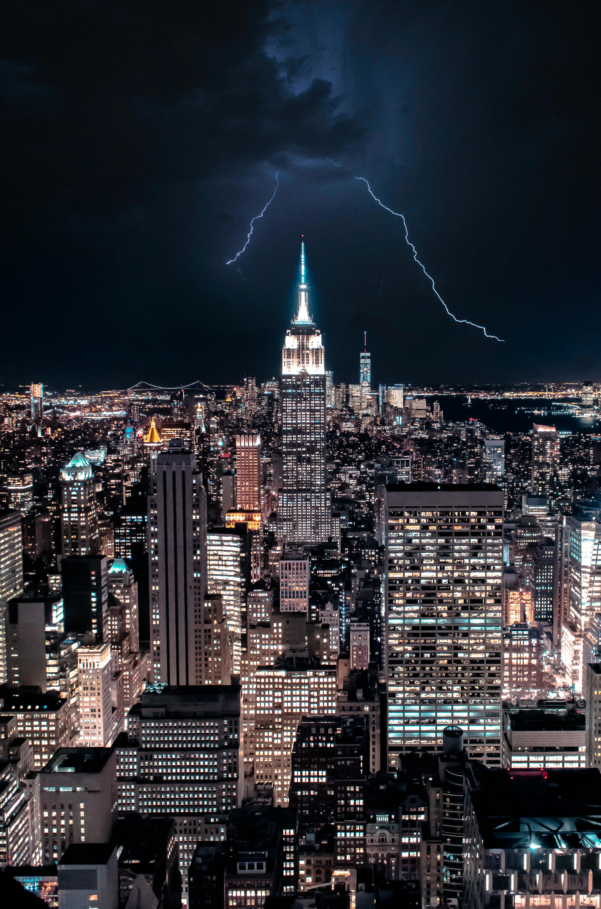 Lightning strikes the Empire State Building at night, illuminating the New York City skyline.