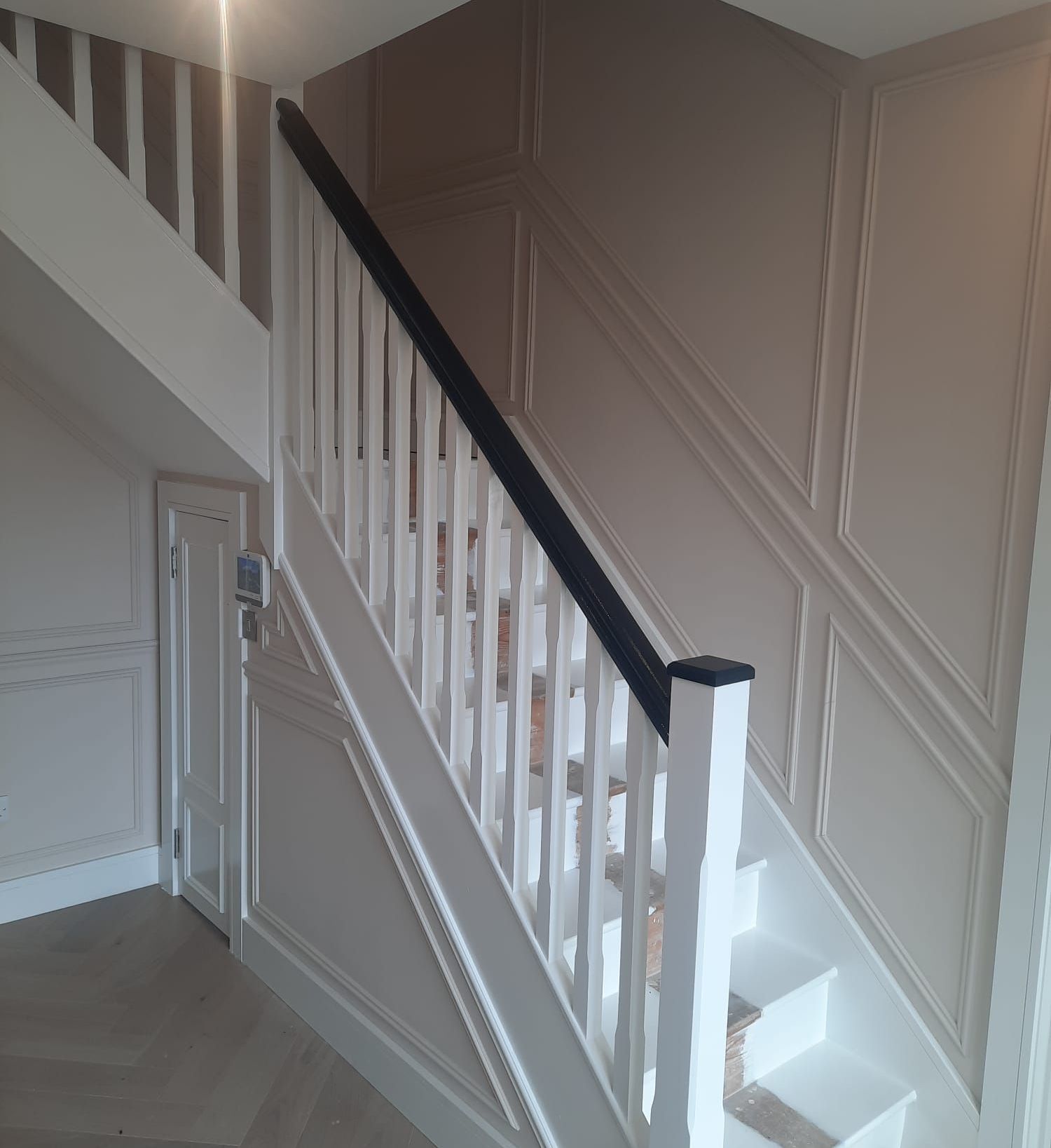 A white staircase with a black railing in a room