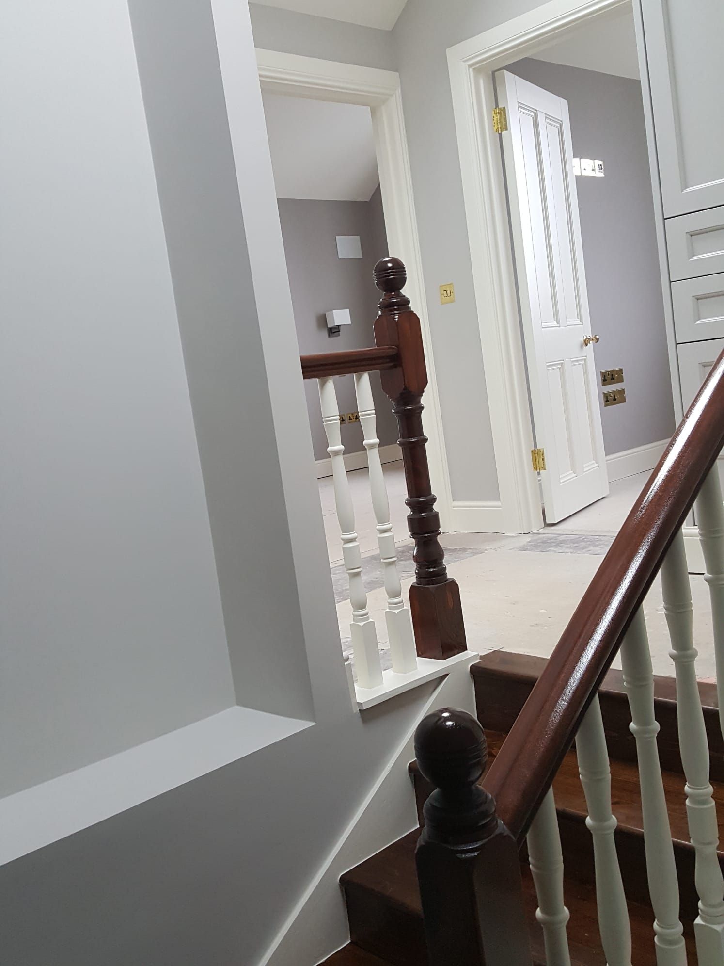 A staircase with a wooden railing and a door in the background.