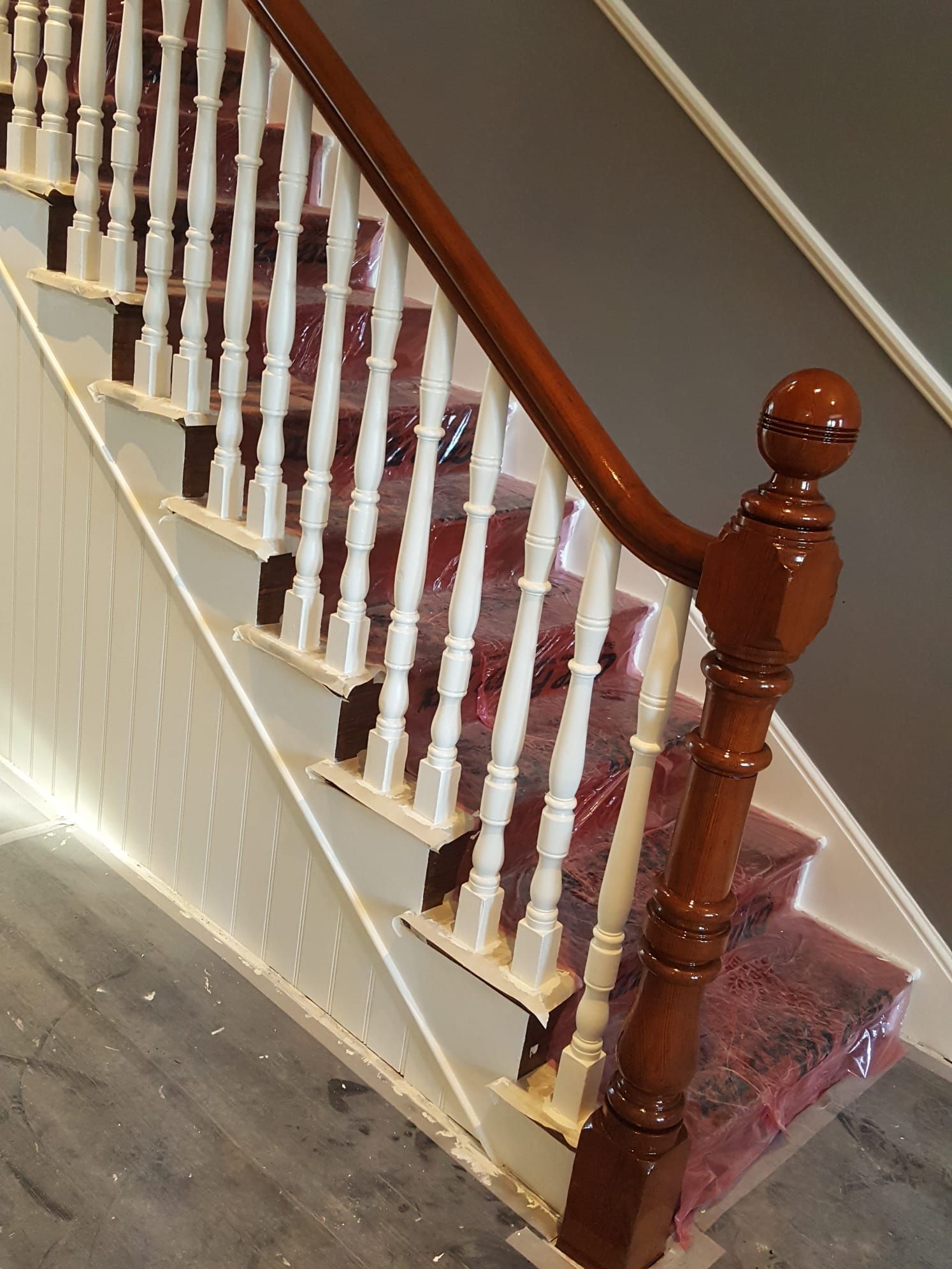 A wooden staircase with white railings and a red carpet