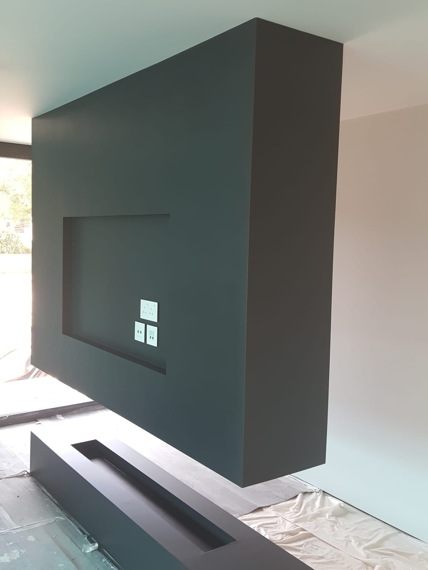 A large black box is hanging from the ceiling in a living room.