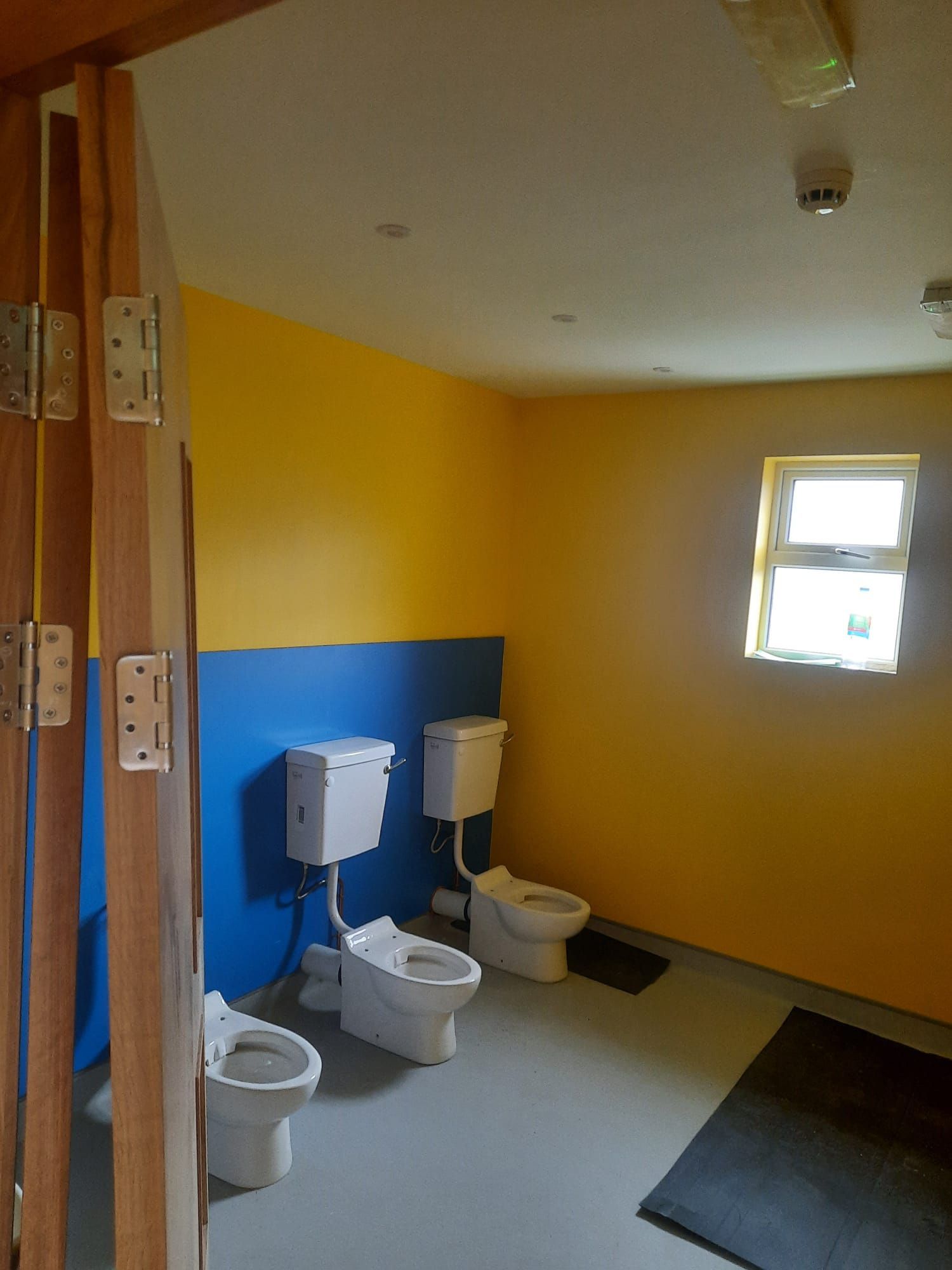 A bathroom with three toilets and a window
