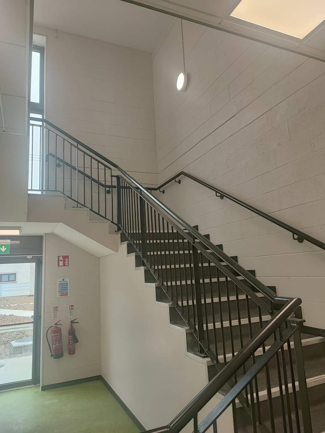 A staircase in a building with a fire extinguisher on the wall.