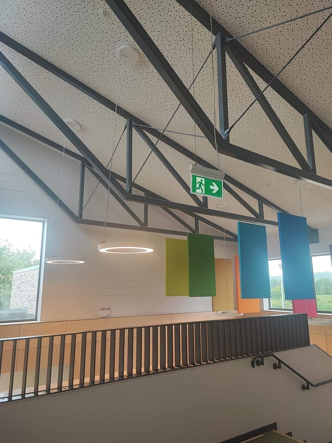 A green exit sign hangs from the ceiling of a building