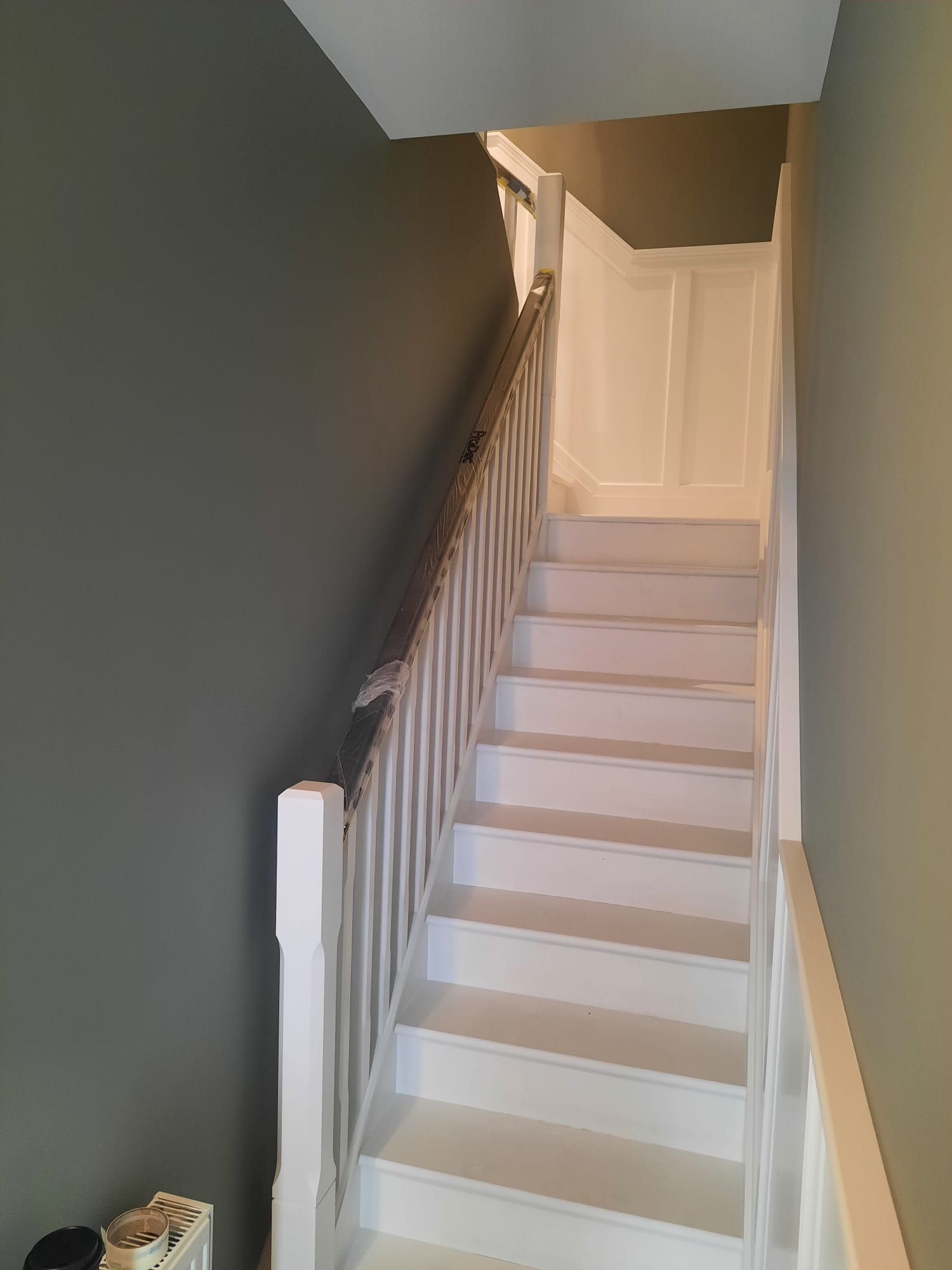 A white staircase with a wooden railing leading up to the second floor of a house.