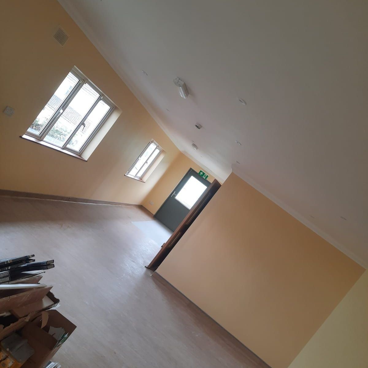 An empty room with a green exit sign on the ceiling