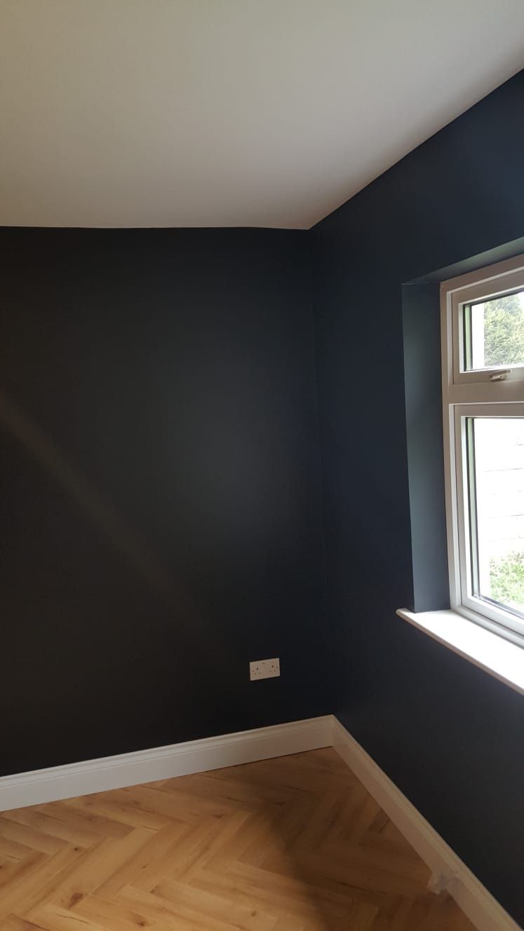 An empty room with black walls and a window
