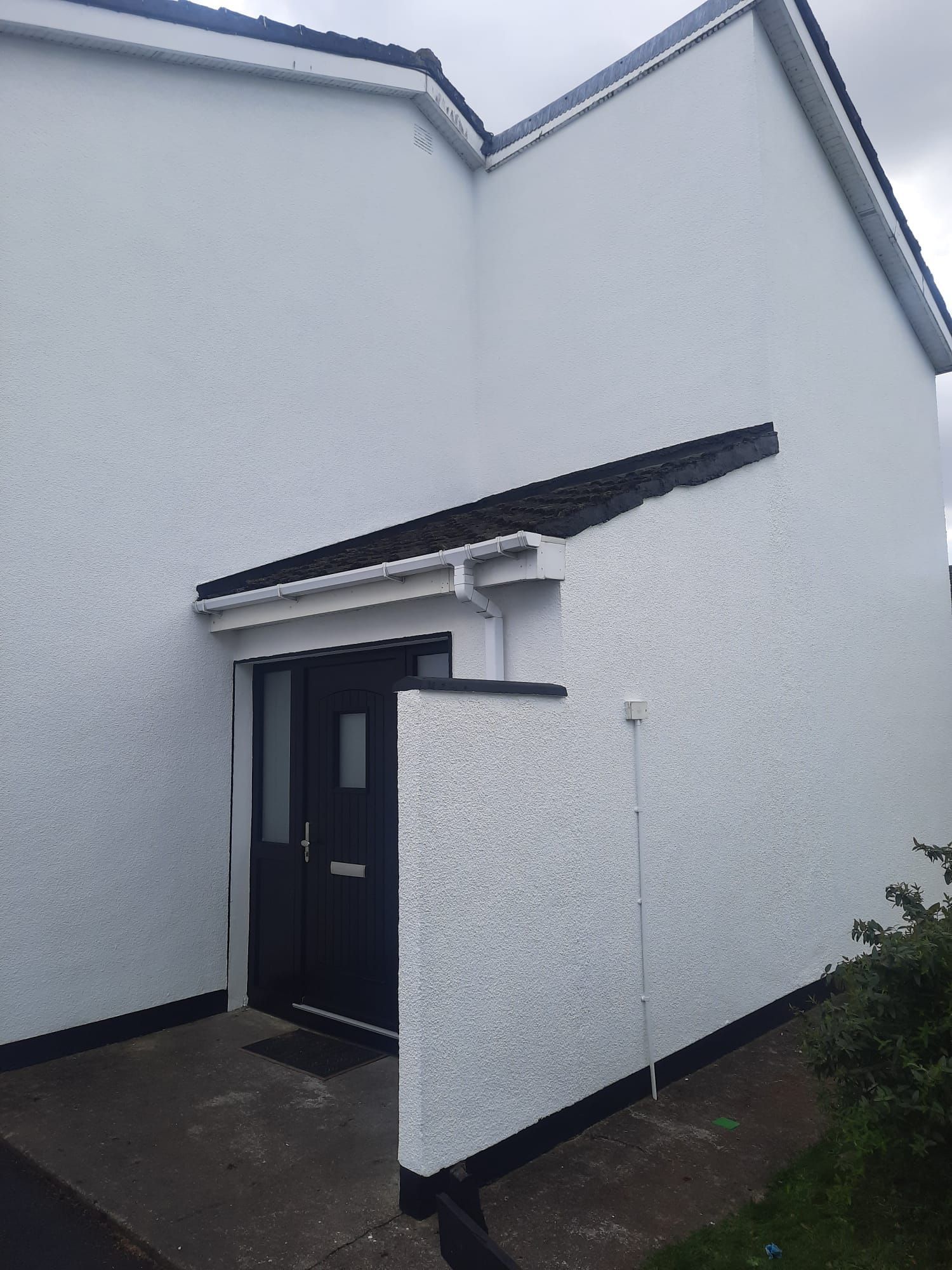 A white house with a black door and a black roof