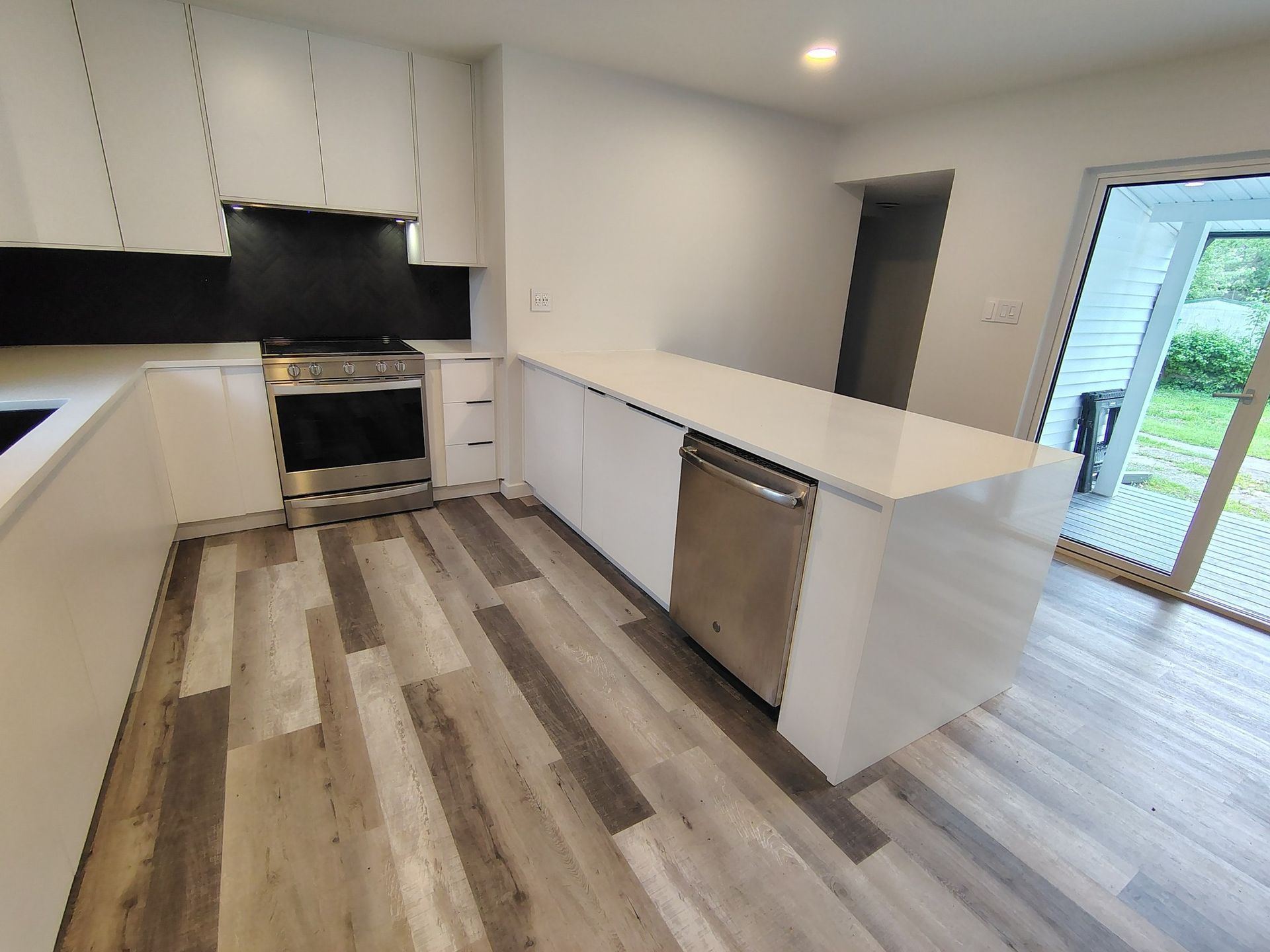 Modern white kitchen with a stainless steel dishwasher and a long countertop.