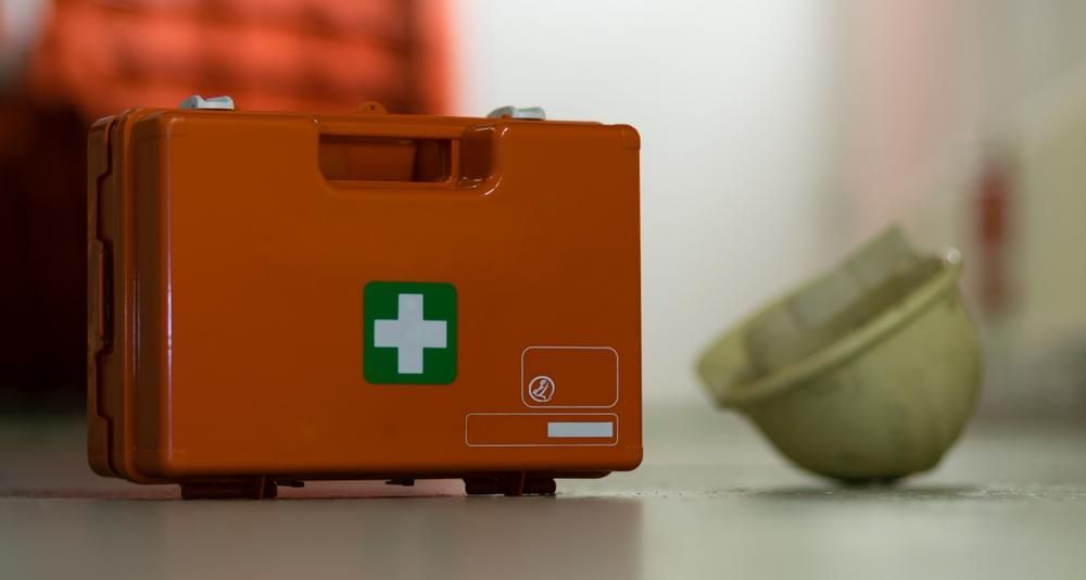 A First Aid Kit Is Sitting On A Table Next To A Helmet — Accidental Health & Safety NQ & Mt Isa In Longreach, QLD