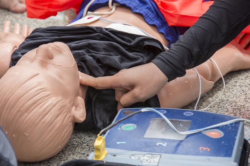 A Person Is Putting A Defibrillator On A Mannequin — Accidental Health & Safety NQ & Mt Isa In Longreach, QLD