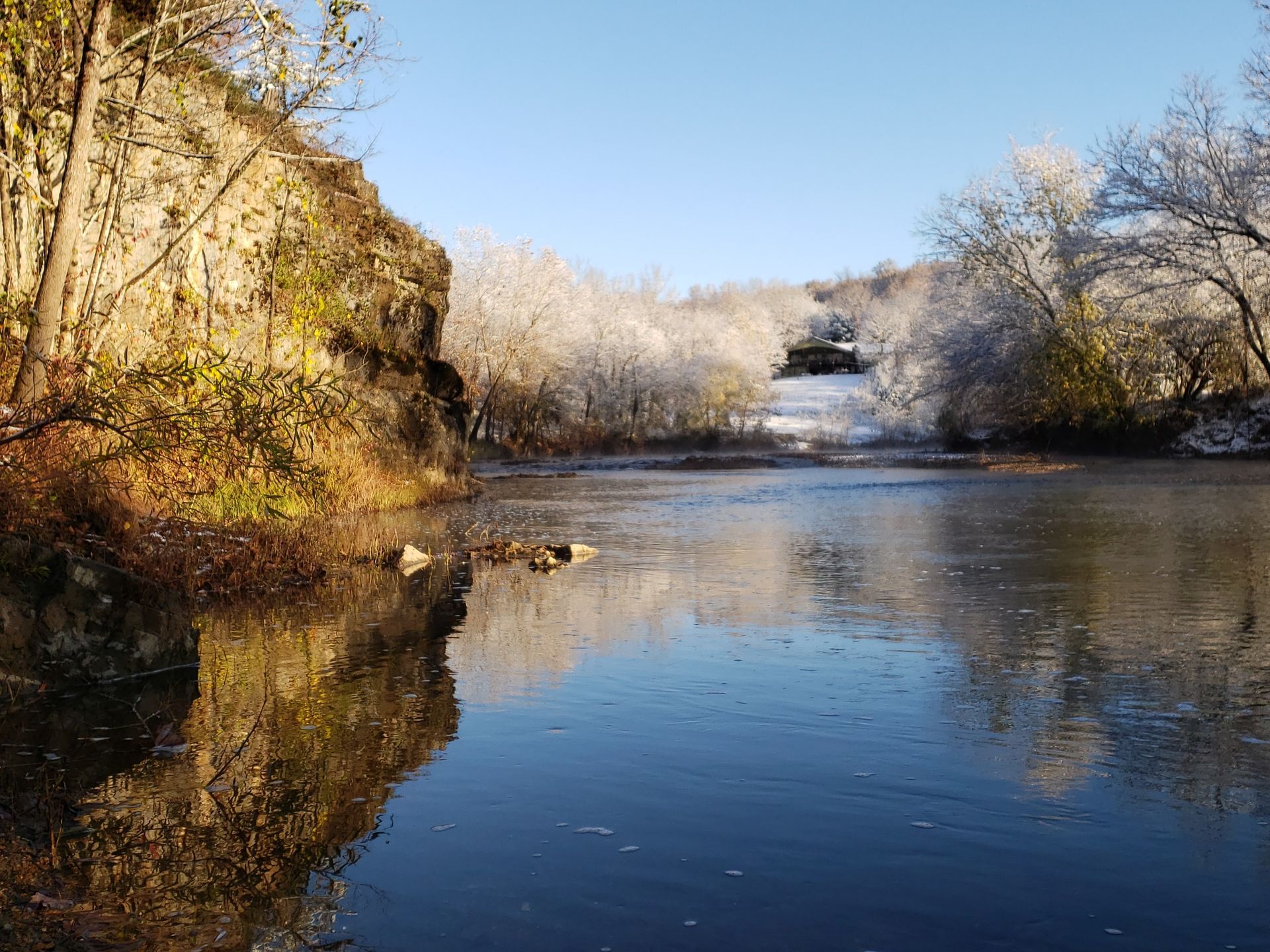 Calm river reflecting frosted trees and blue sky on a sunny winter day