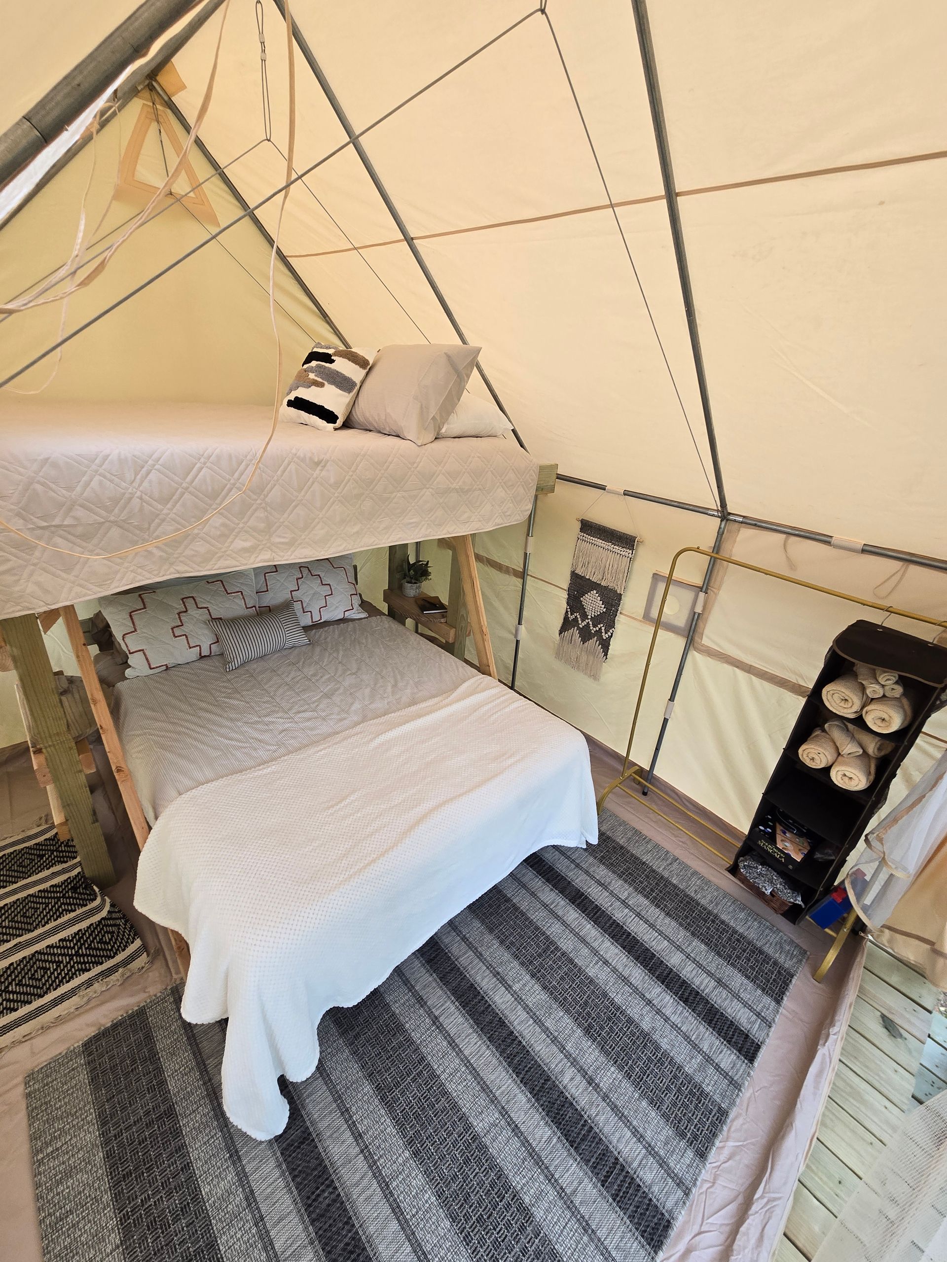 Cozy glamping tent interior with a bed, striped rug, and warm string lights