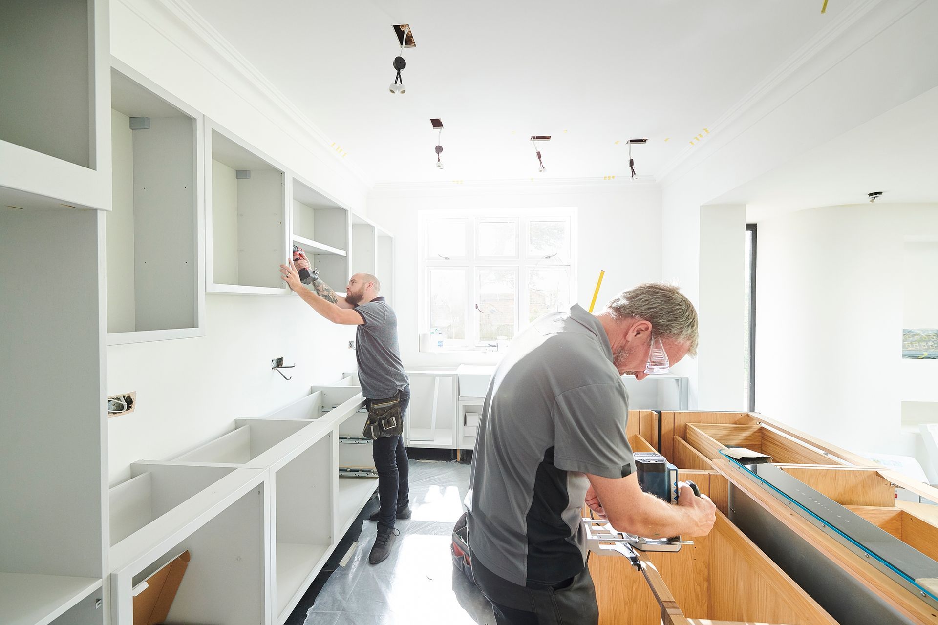 Two men are installing cabinets in a kitchen. Two men are installing cabinets in a kitchen.
