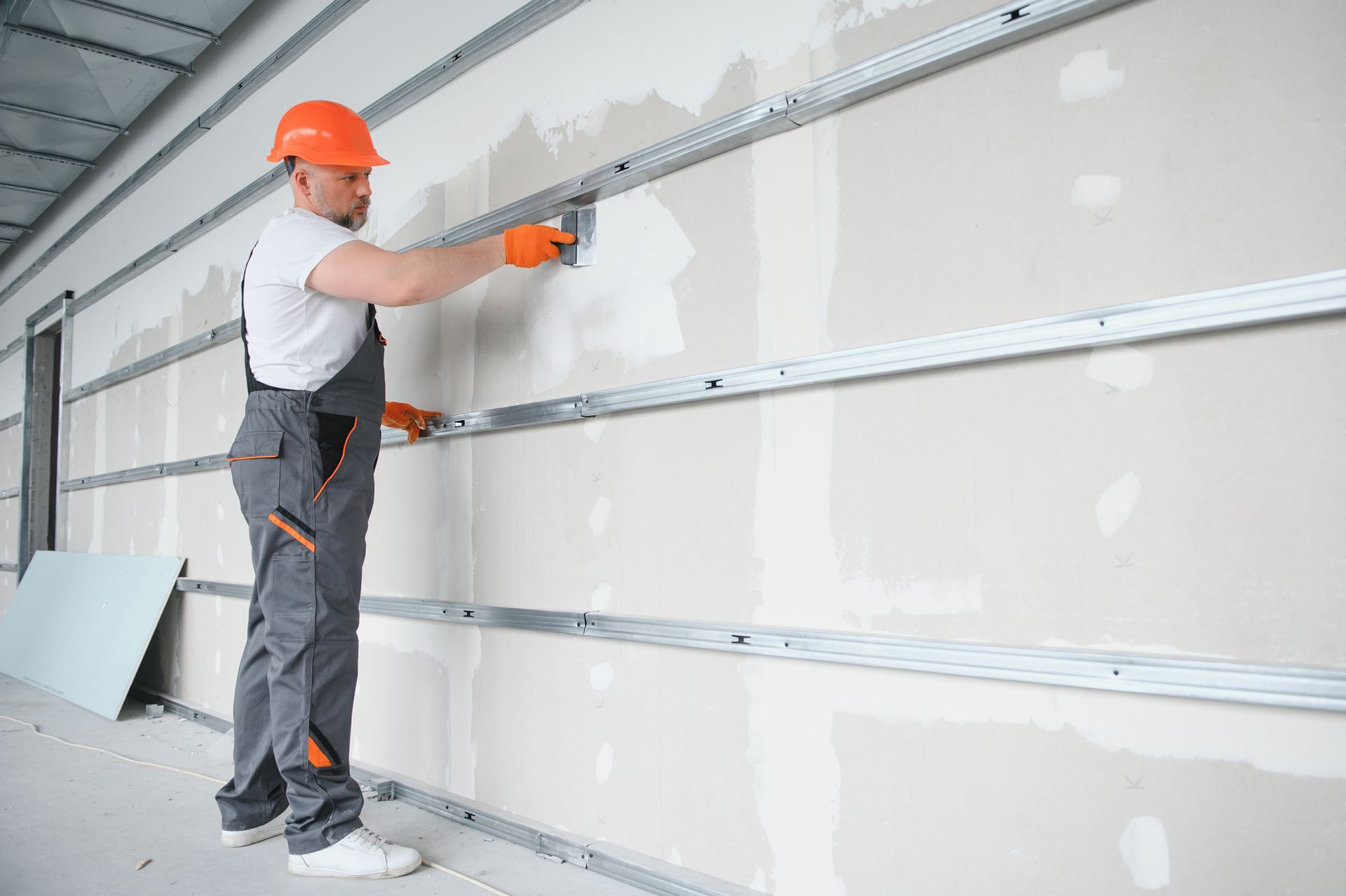 A man is plastering a wall with a spatula. A man is plastering a wall with a spatula.